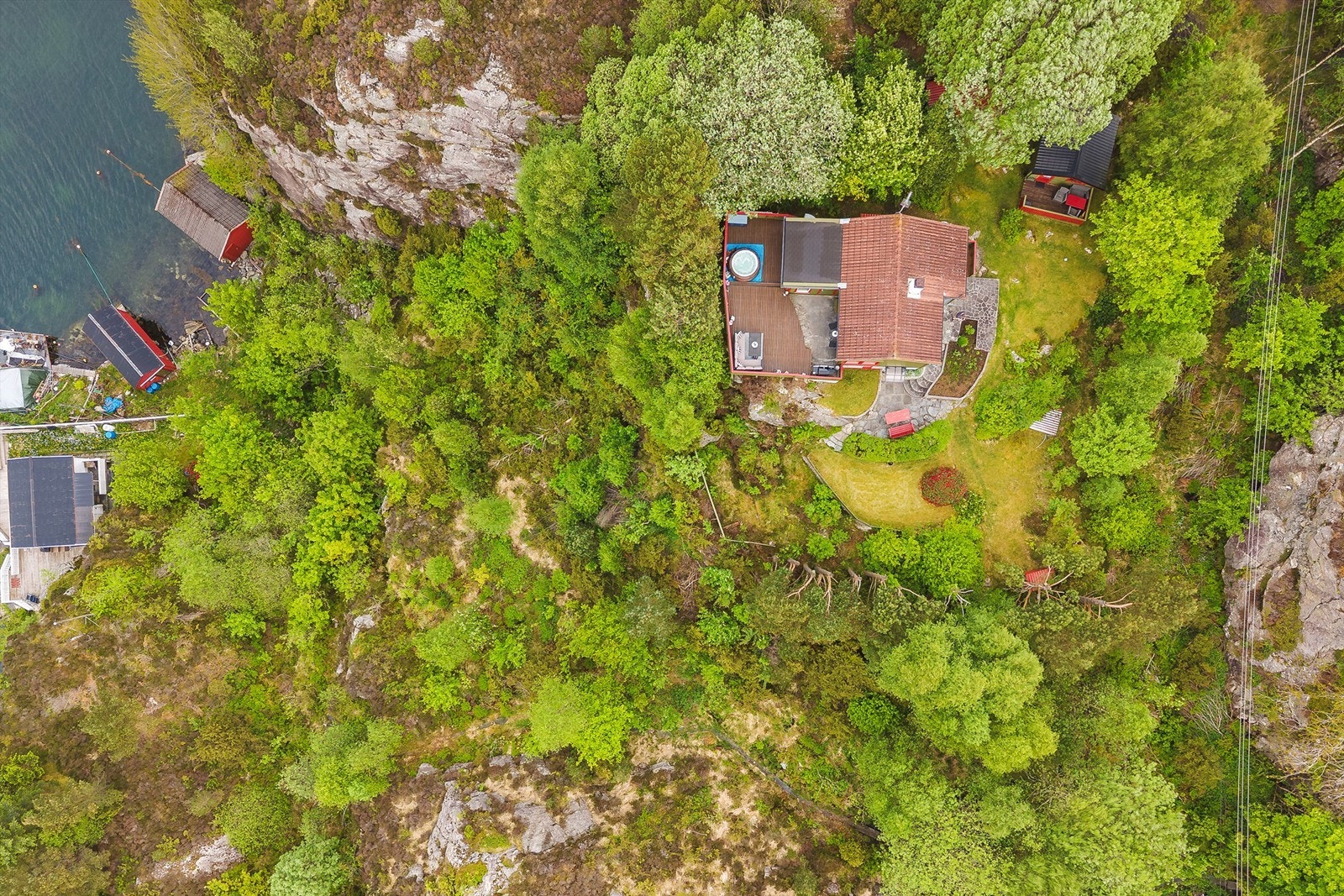 Dronebilde av eiendommen med båtopptrekk i viken nedenfor. Galleribilde