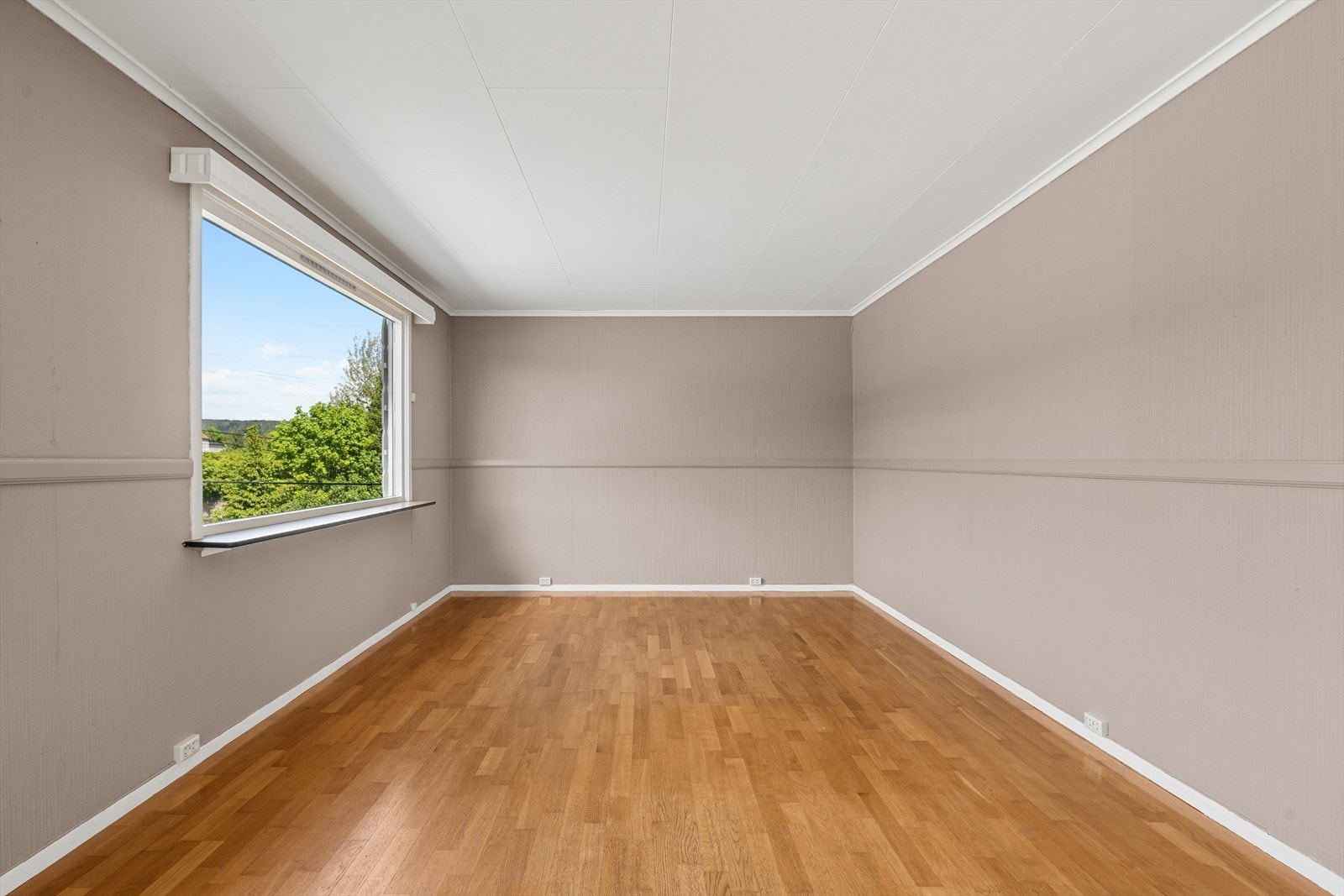Overflatene i stuen består av parkett på gulv og tapetserte vegger. Galleribilde