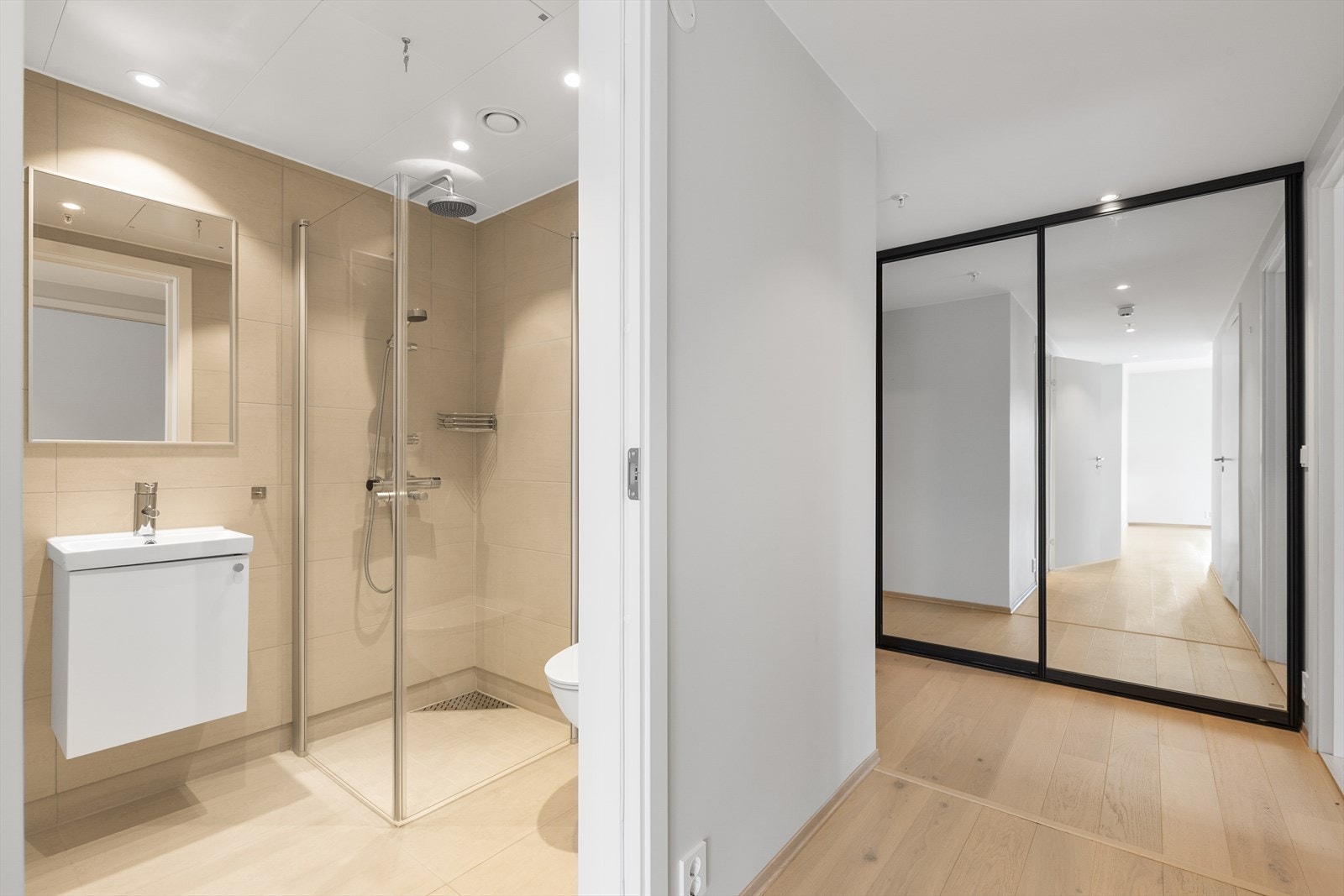 Det andre badet har tilsvarende standard med flislagte gulv og vegger. Rommet er utstyrt med dusjnisje med innfellbare dusjdører, veggmontert toalett og innredning med heldekkende vask, underskap med slett front og speil. Galleribilde