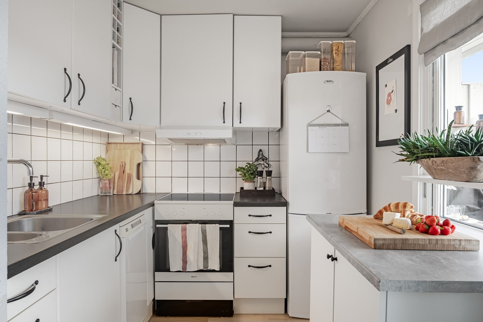 Lys kjøkkeninnredning fra 2007 med glatte hvite fronter og laminert benkeplate med nedfelt oppvaskkum. Galleribilde