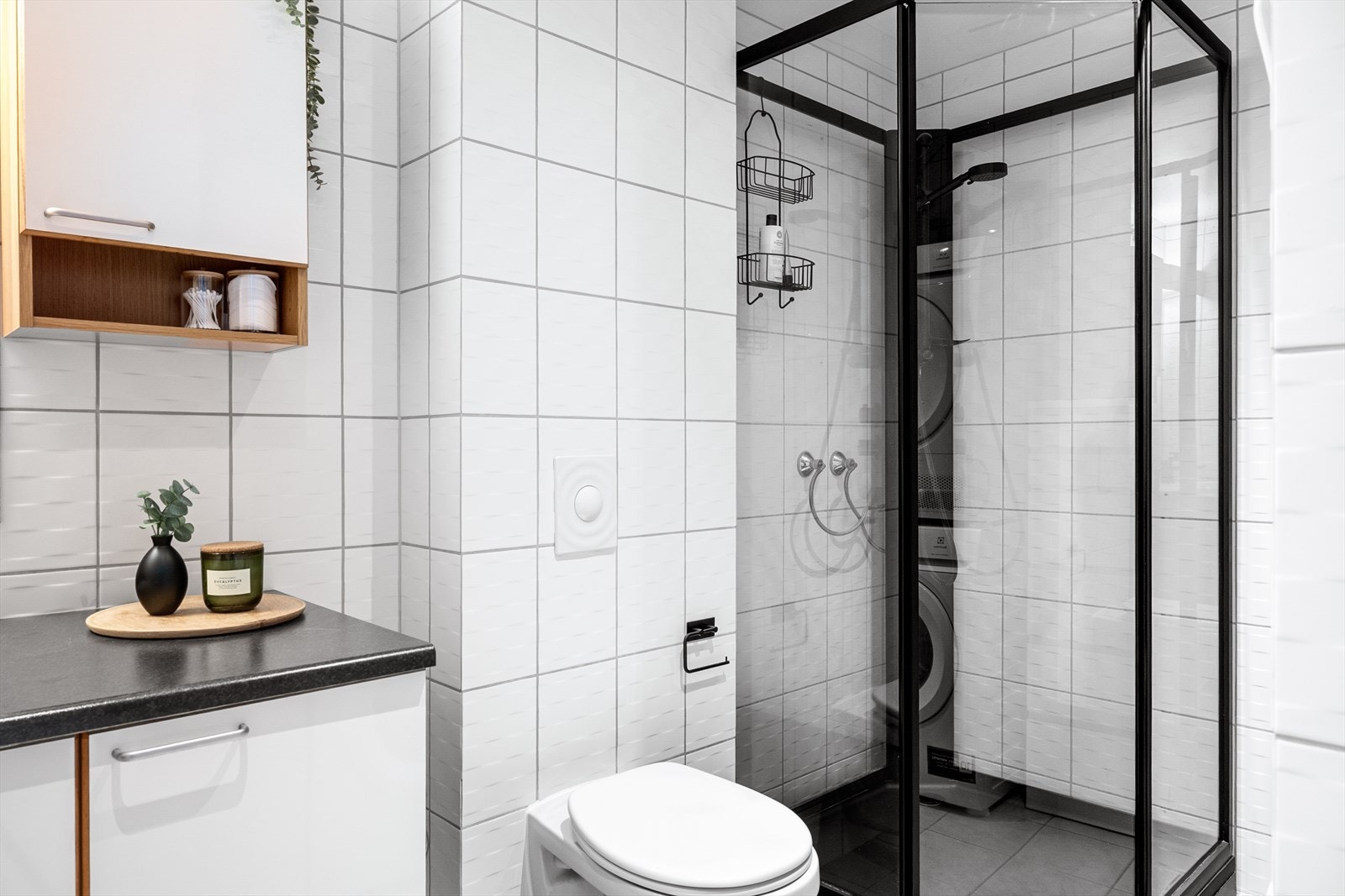 Badet er utstyrt med dusjkabinett med elegante svarte rammer, som gir rommet et moderne og tidløst preg. Galleribilde