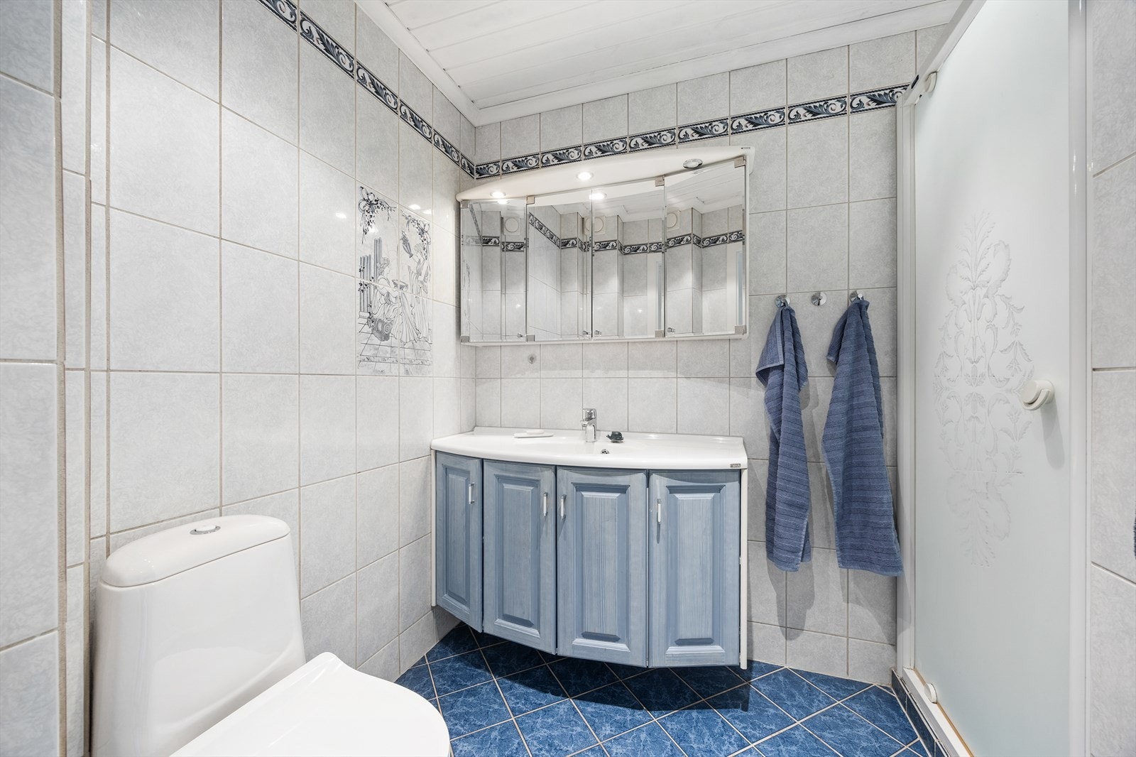 Badet i første etasje har flislagte vegger, panel i himling og dusjløsning. Galleribilde