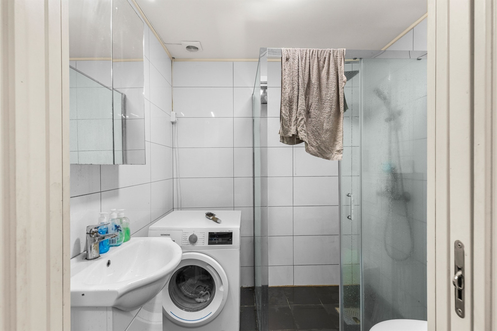 Flislagt bad på 3,5 kvm innredet med servantskap med speil, toalett, dusjhjørne og opplegg for vaskemaskin. Badet er opprinnelig byggemeldt som en del av garasjen. Det er ikke søkt bruksendring fra tilleggsdel til hoveddel. Galleribilde