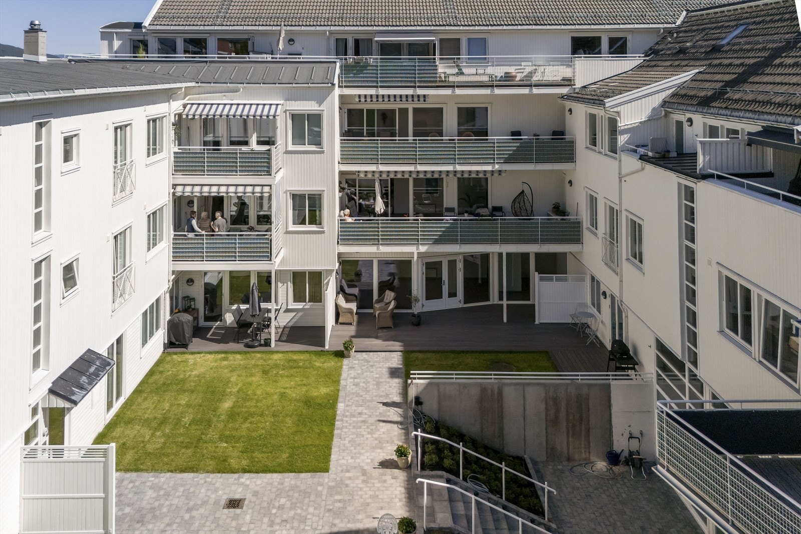 Velholdt bakgård med plen, belegningsstein og beplantninger Galleribilde