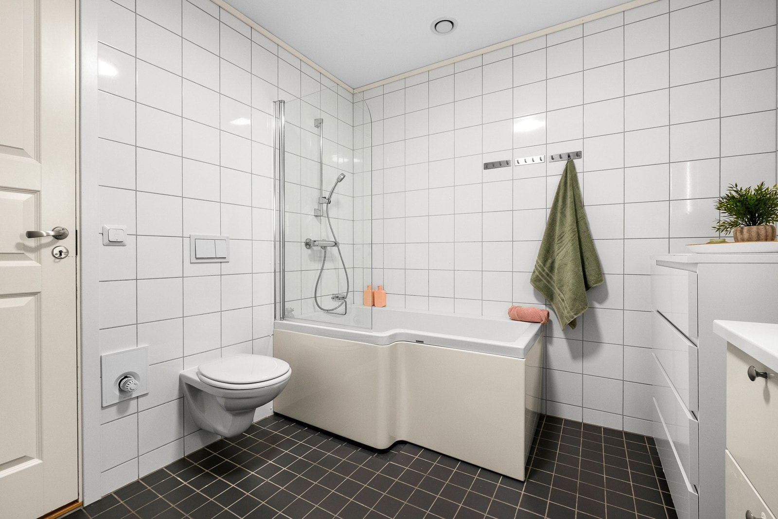 Badet er innredet med veggmontert toalett, badekar med dusjløsning og servantinnredning. Galleribilde