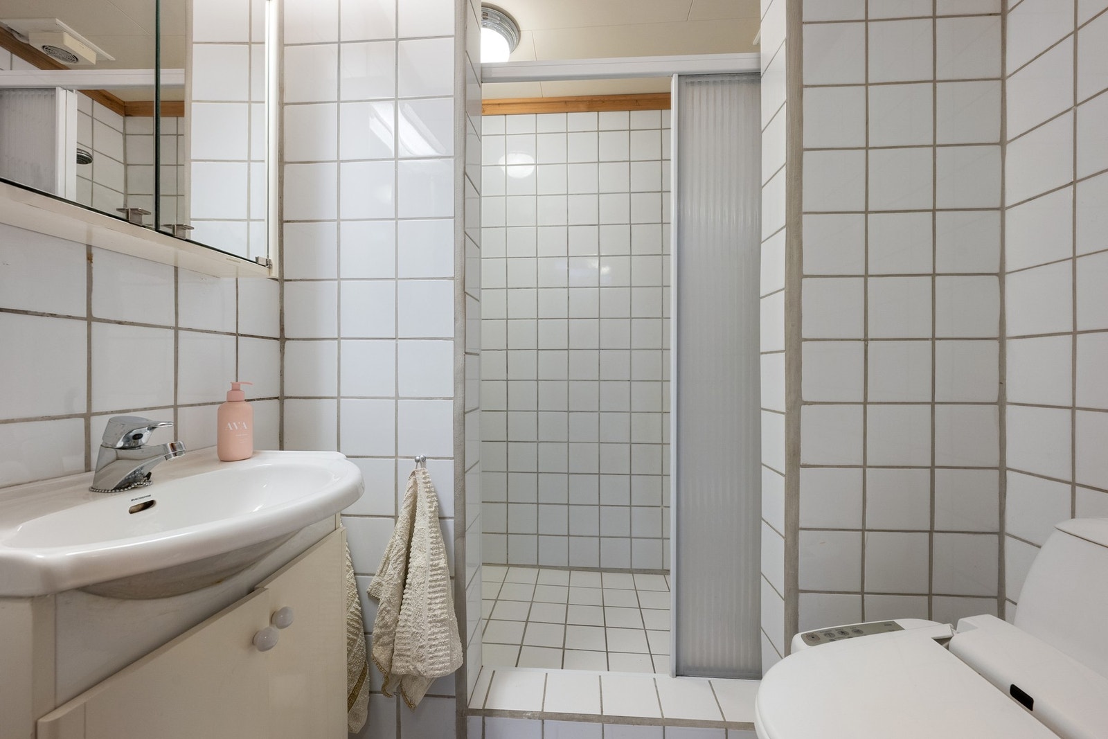 Bad i kjeller med flislagte overflater, dusjnisje, servantinnredning og toalett. Galleribilde