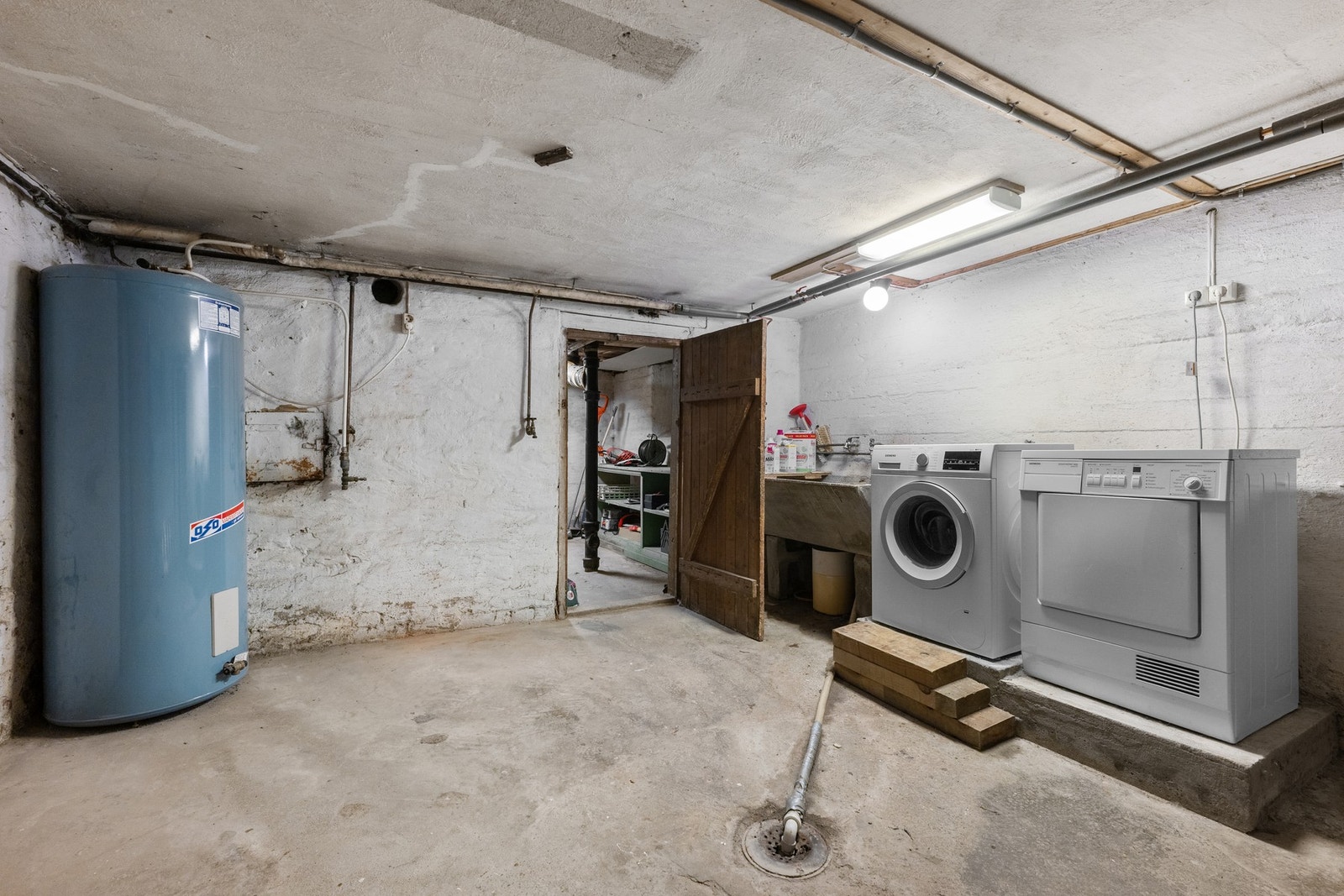 Praktisk vaskekjeller med varmtvannsbereder, utslagsvask og plass til vaskemaskin og tørketrommel. Galleribilde