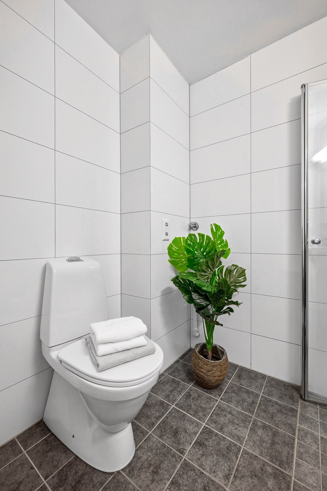 Badet er utstyrt med frittstående toalett, dusjhjørne med innfellbare glassdører og blandebatteri og baderomsmøbel med heldekkende servant, ettgrepsbatteri, speil og belysning. Galleribilde