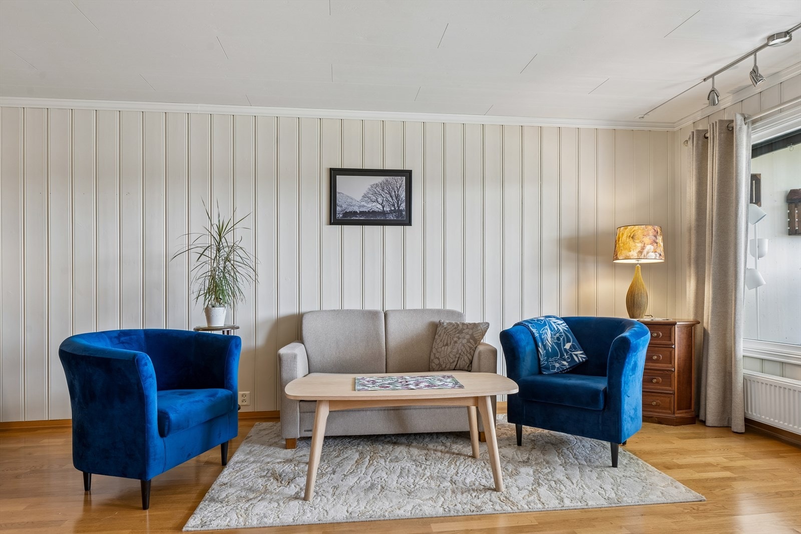 Stuen har parkett på gulvet og vegger med malt panel. Oppvarming via fjernvarme. Galleribilde