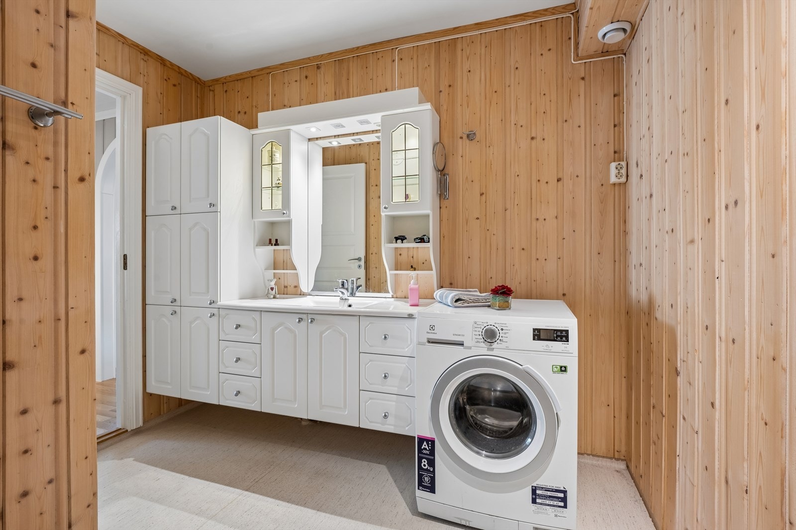 Kombinert bad og vaskerom med belegg på gulv, trepanel på vegger og opplegg for vaskemaskin. Galleribilde
