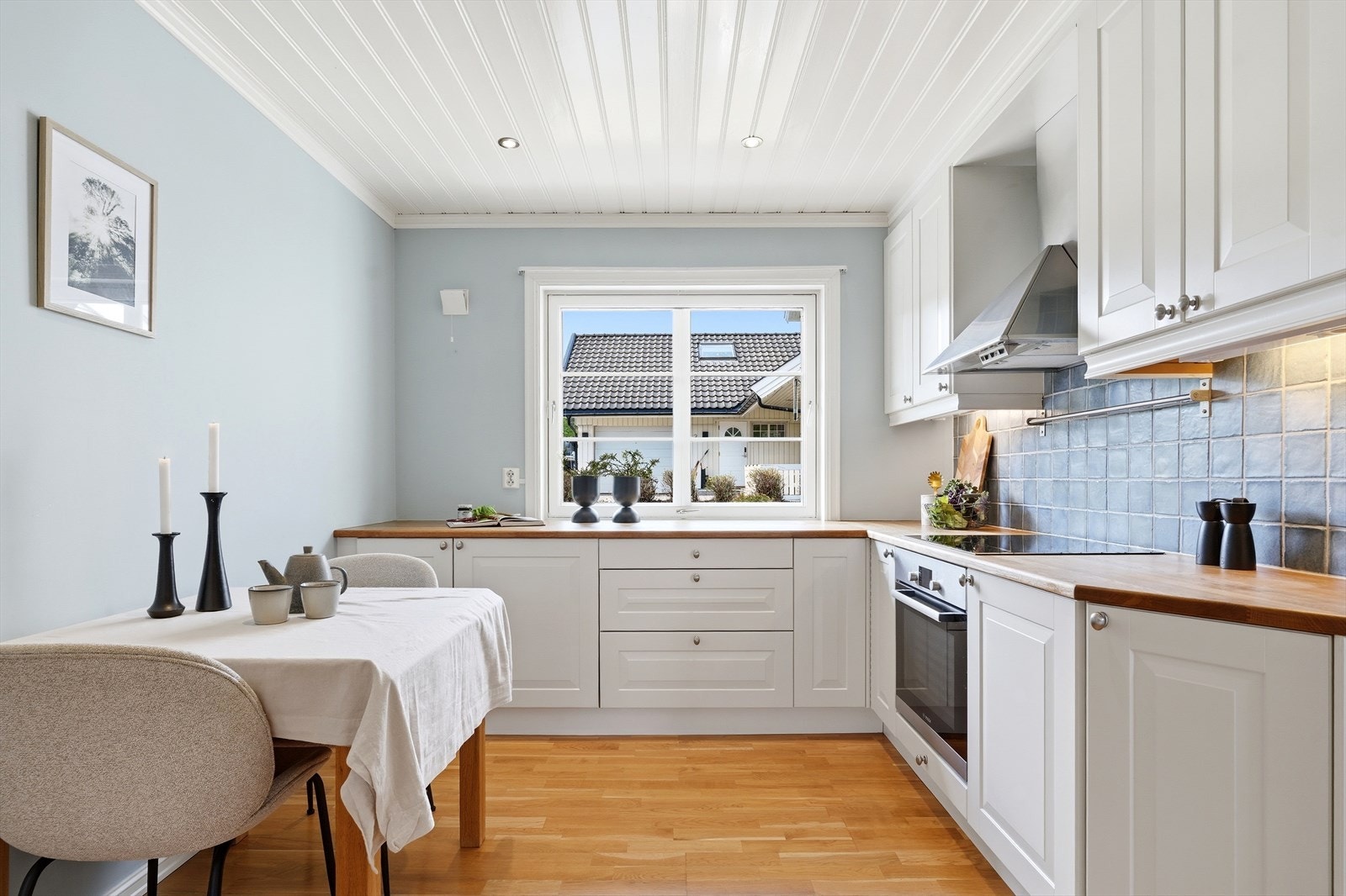 Kjøkken med profilerte fronter, nedfelt komfyrtopp og ventilator. Her er det også plass til en liten spiseplass. Galleribilde