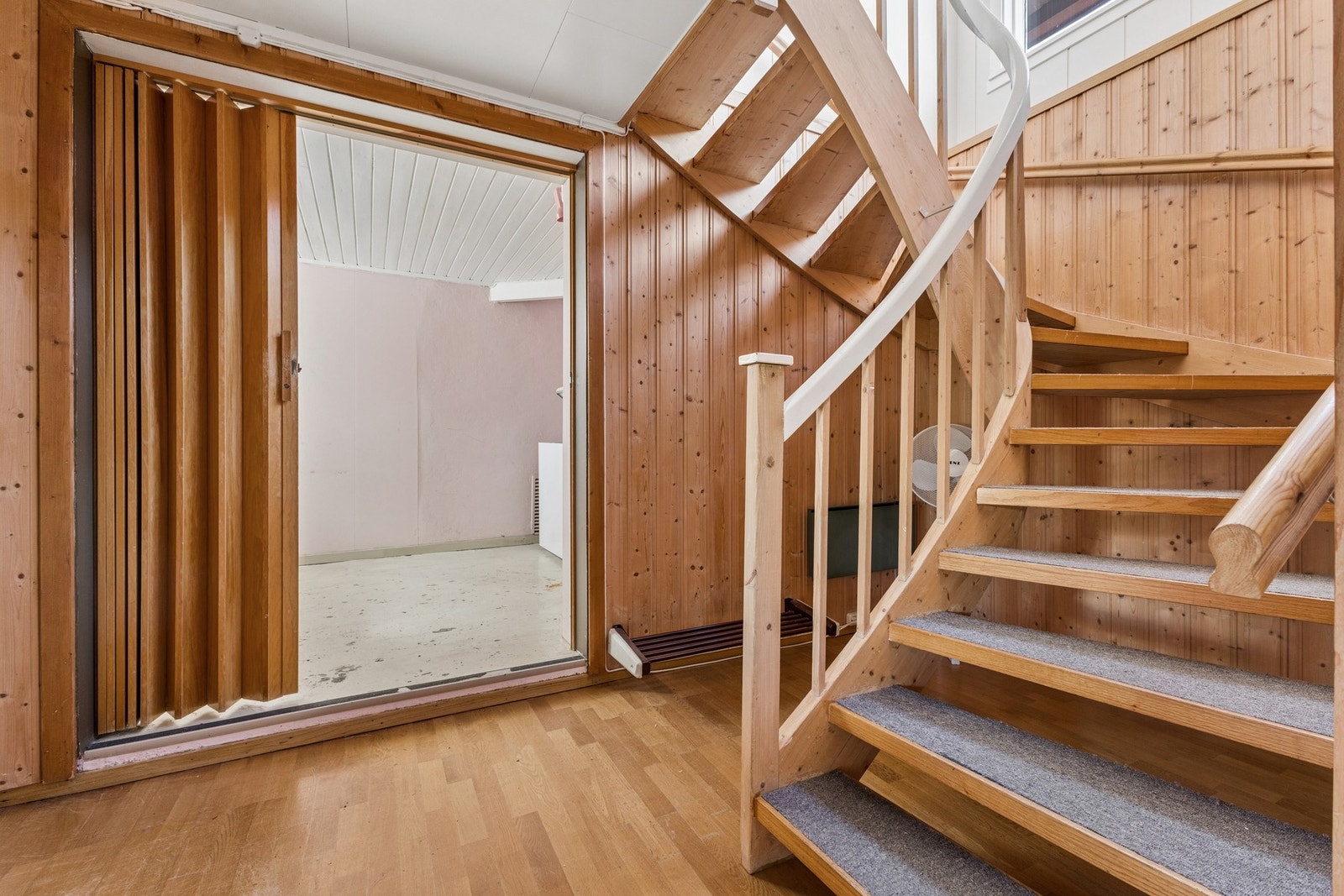 En foldedør i trelameller skiller rommene i kjellergangen. Galleribilde