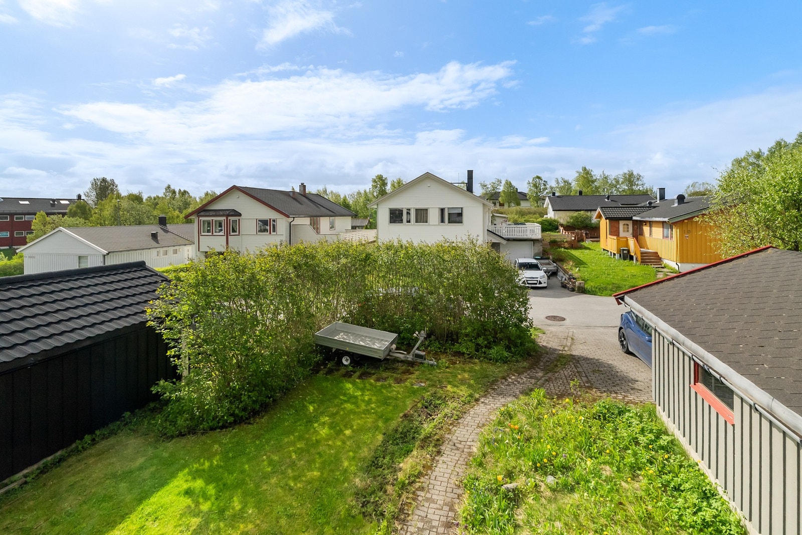 Tomten er opparbeidet med gruset adkomst, plen og beplantning. Galleribilde