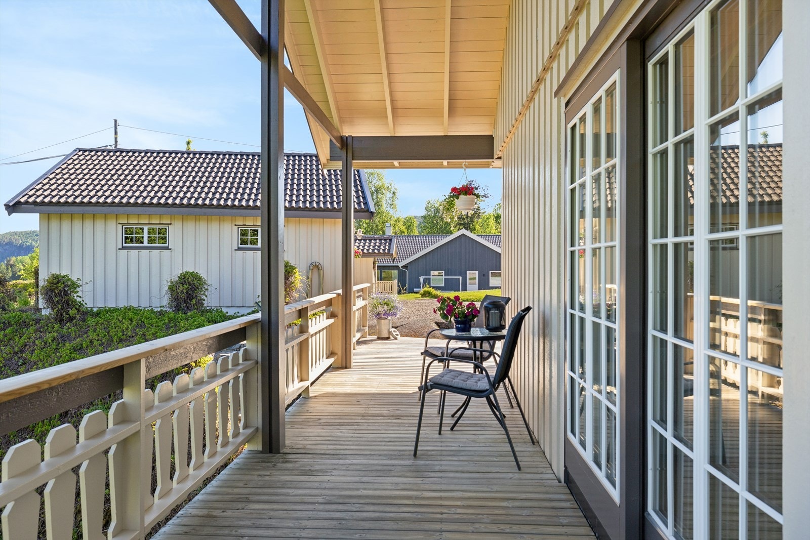 Terrassen glir naturlig over i en overbygd veranda med flott utsikt over hagen. Imponerende takhøyde bidrar til en luftig og innbydende atmosfære. Galleribilde