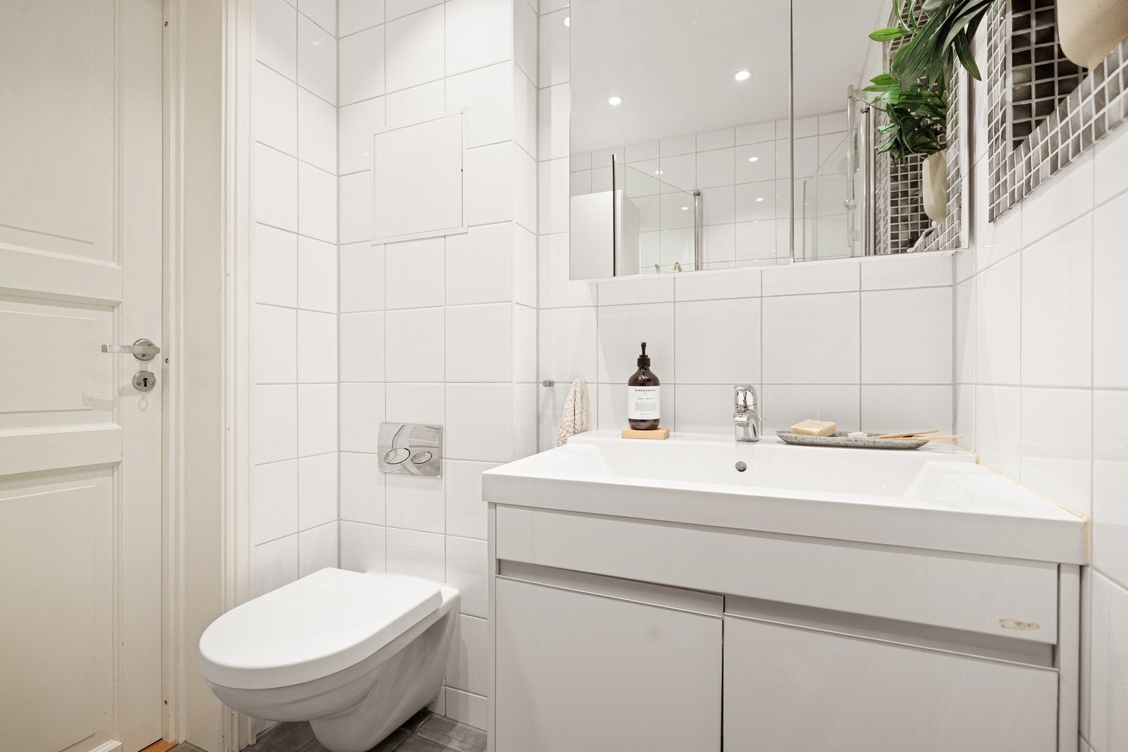 Badet utstyrt med servantinnredning med speilskap over, toalett og dusjhjørne med glassvegger. Galleribilde