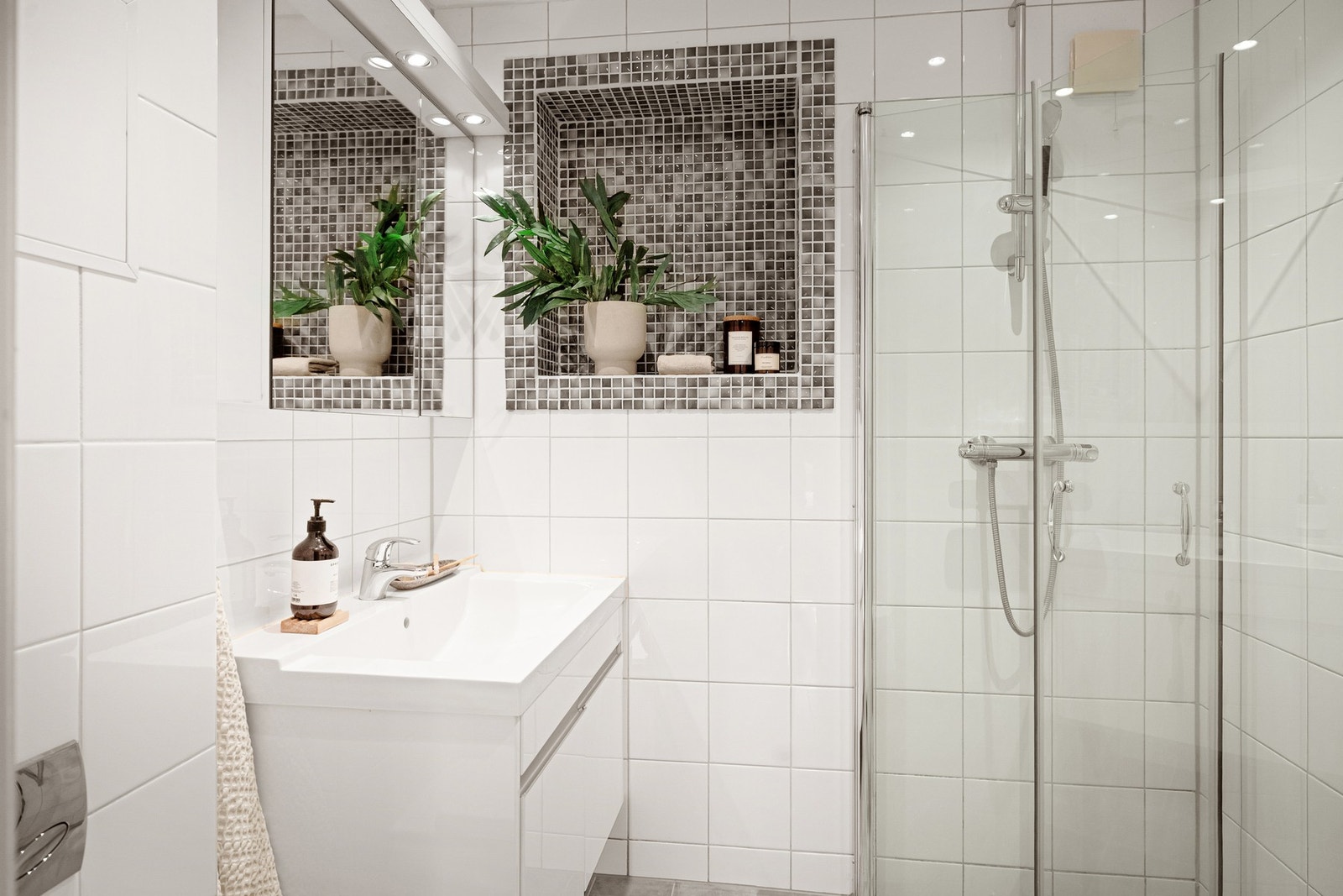 Badet har en lys og tidløs utførelse med flislagte overflater og en praktisk planløsning. Galleribilde