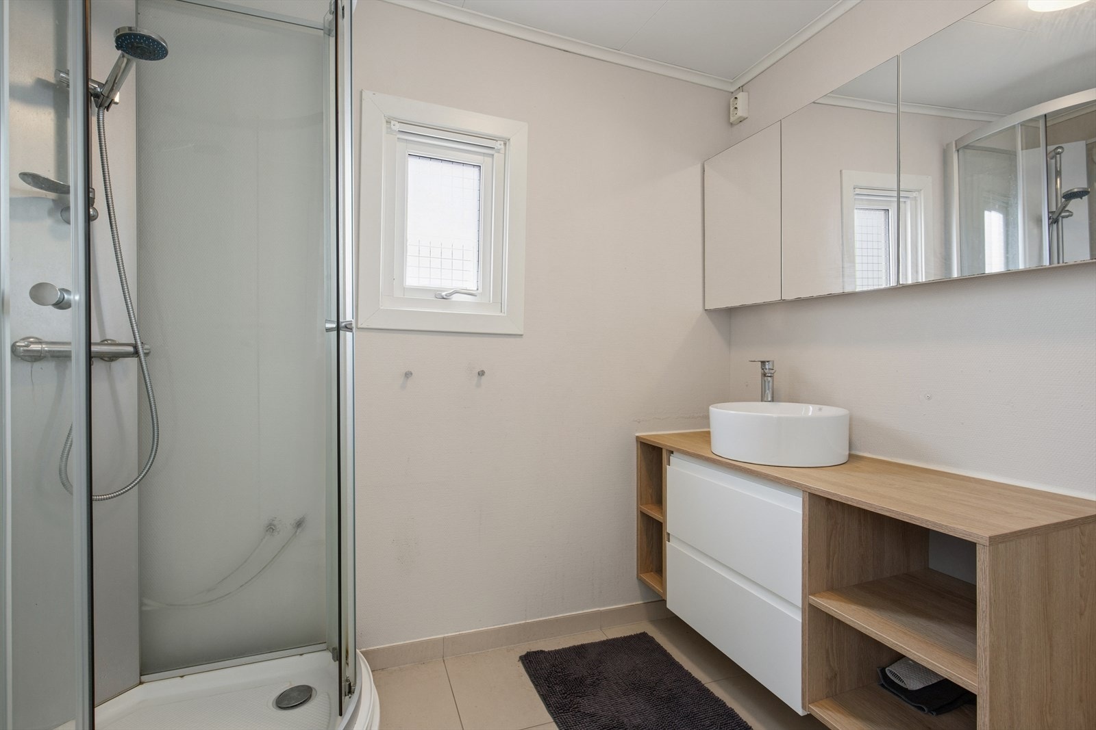 Badets grunnbase er av eldre årstall, med er fornyet med flis i senere tid. Badet er i dag innredet med lyse fliser på gulvet og våtromstapet på vegg. I gulvet har man varmekabler for ekstra komfort. Galleribilde