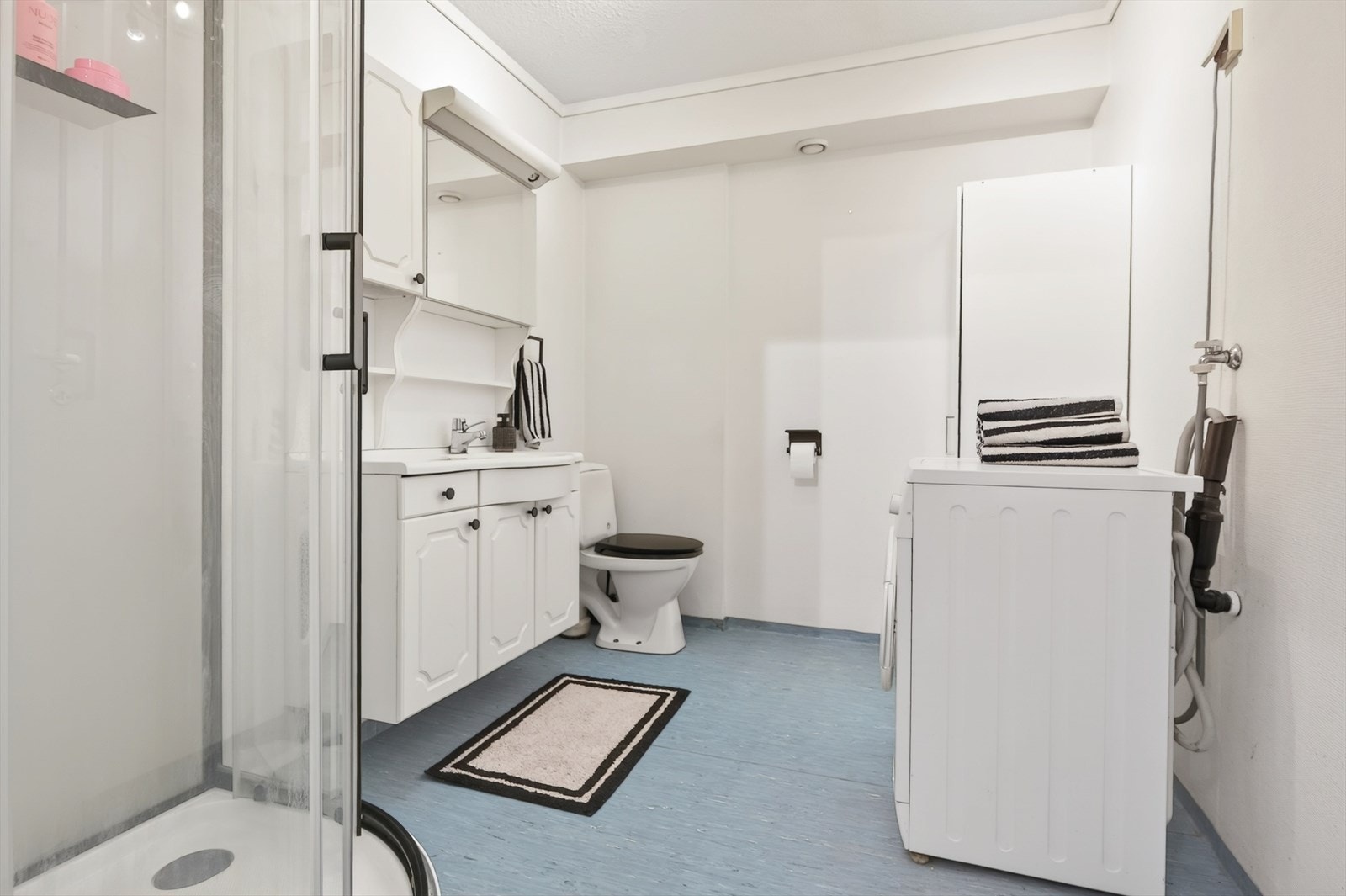 Badet har gulvbelegg, dusjkabinett og opplegg for vaskemaskin. Galleribilde