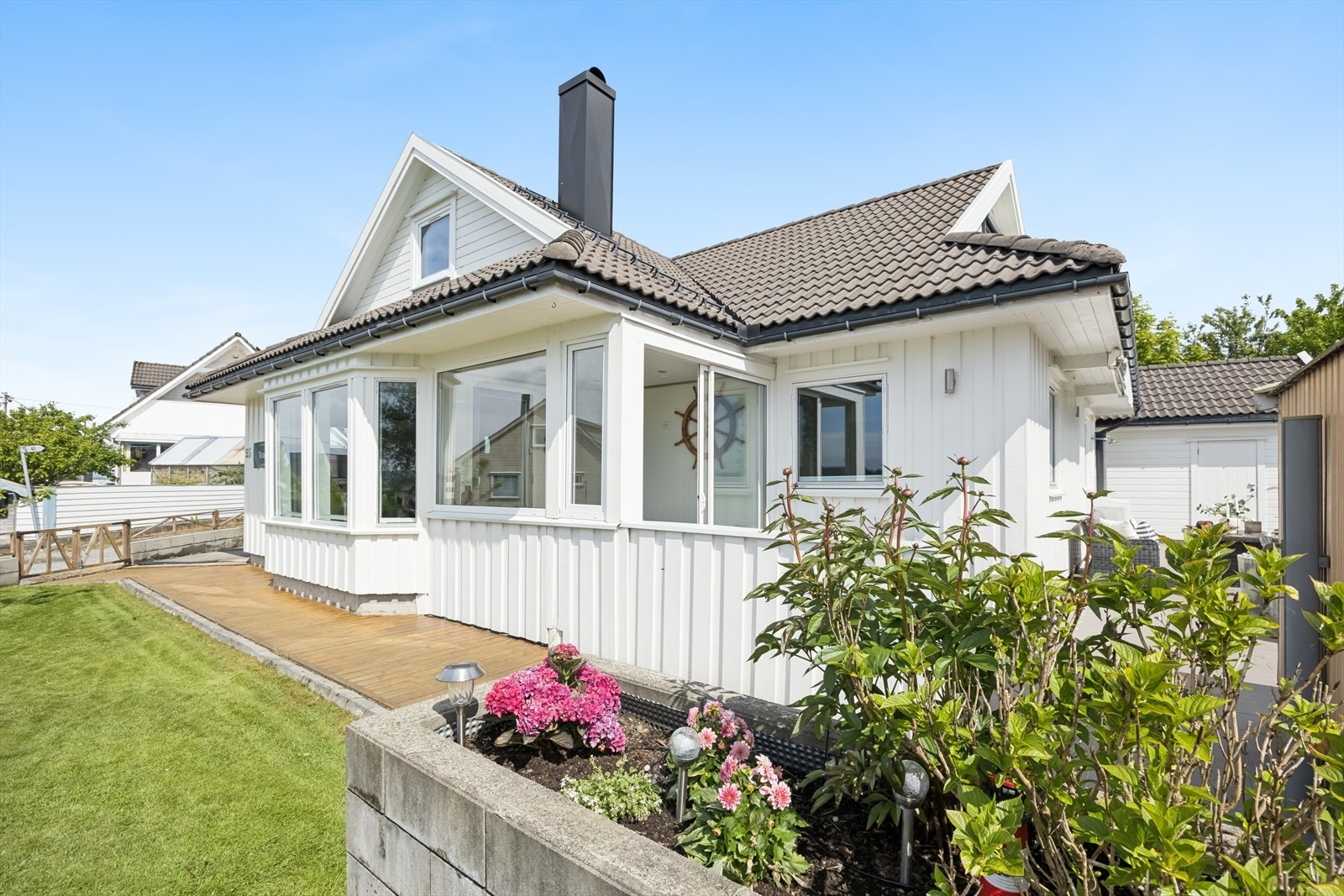 Trivelig uteareal med plen, terrasse og dekorativ beplantning. Galleribilde