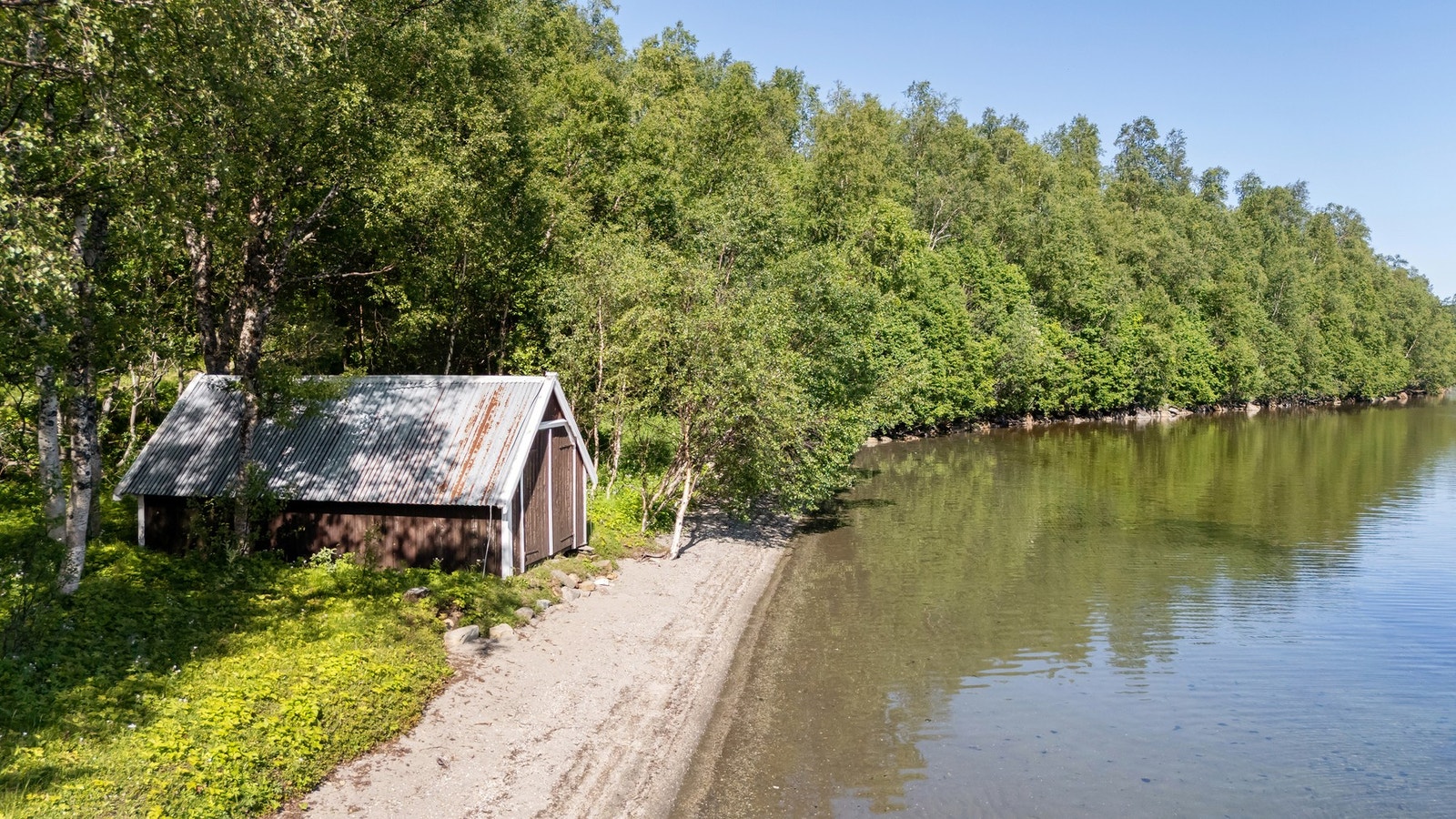Naustet har en flott beliggenhet ved en stille smal strandlinje i idylliske omgivelser Galleribilde