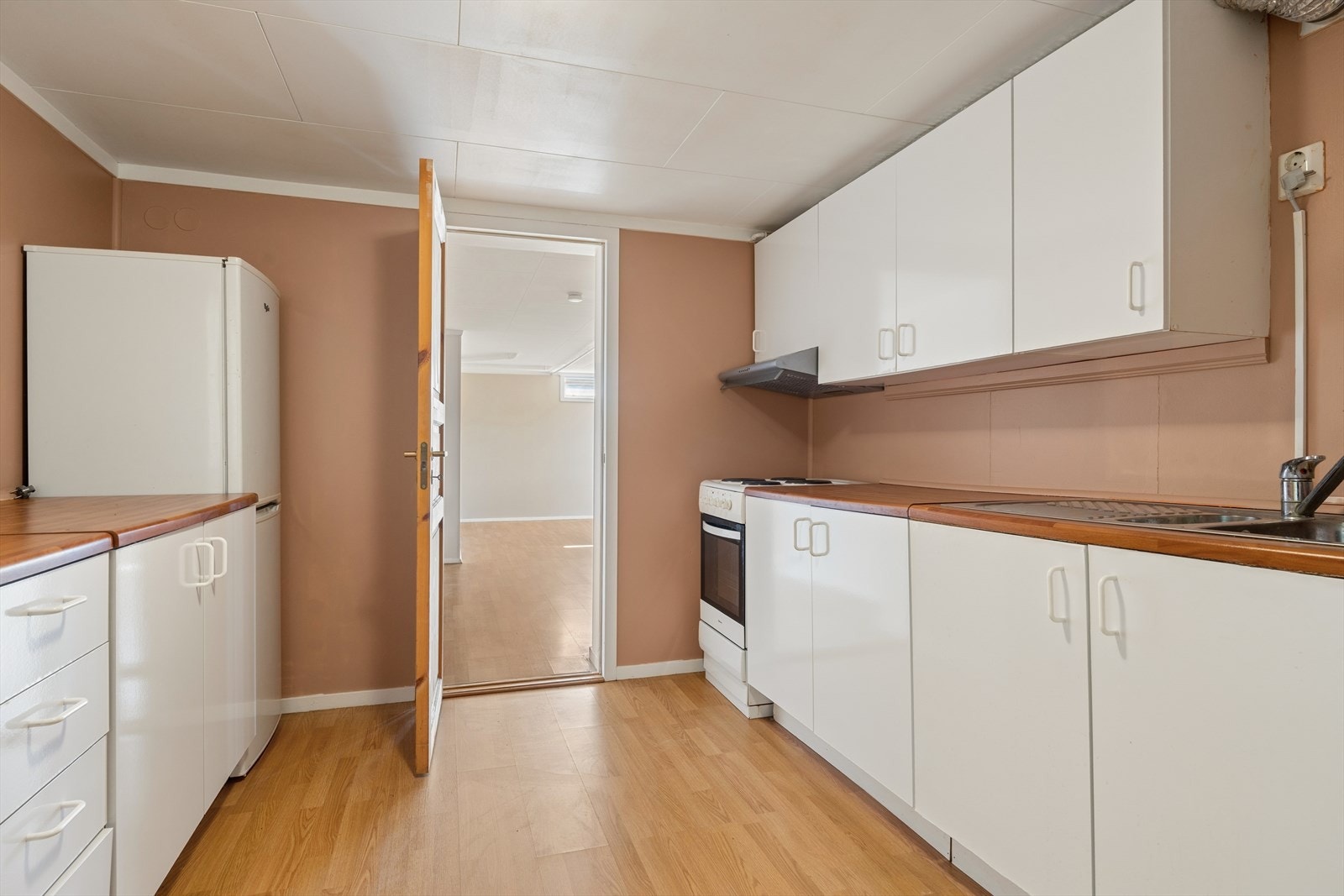 Kjøkkenet i underetasjen har en enkel innredning med hvite, slette fronter og trefarget benkeplate i laminat. Kjøkkenet er ellers utstyrt med frittstående hvitevarer og kjøkkenventilatoren med avtrekk ut, men med redusert funksjon (se "ferdigattest"). Galleribilde