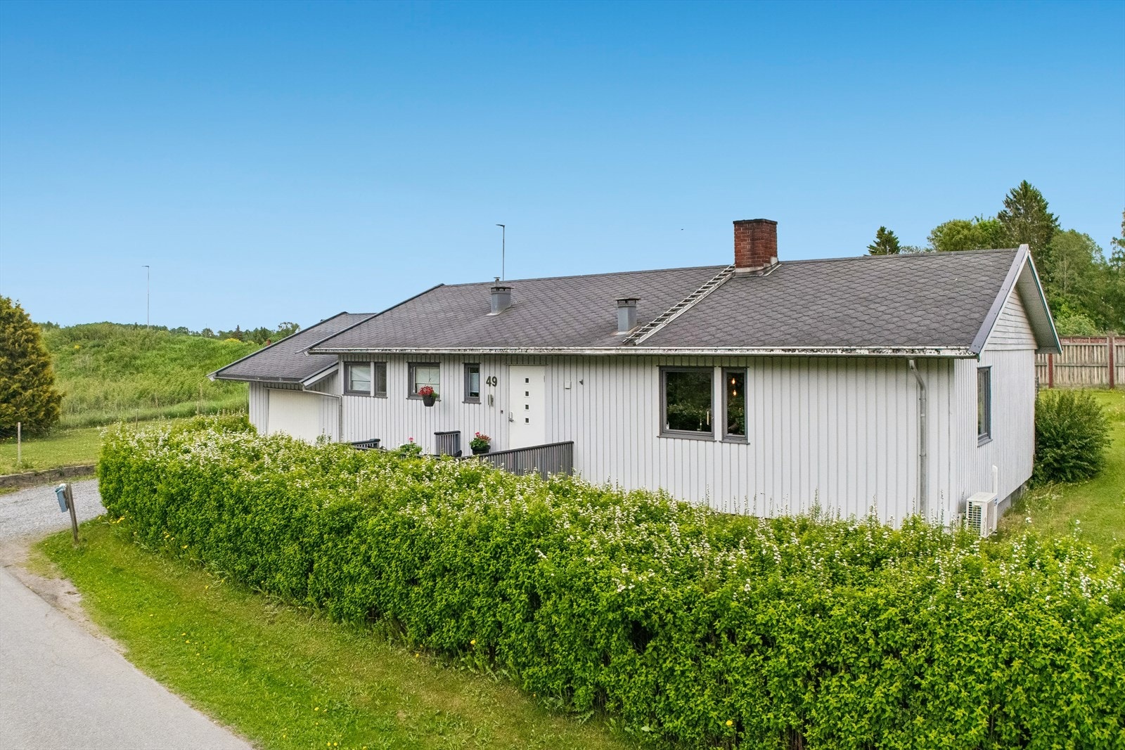 Fasaden har stående og liggende bordkledning, pappshingel på taket og en praktisk, lettstelt boligform over én hovedetasje med kjeller. Galleribilde