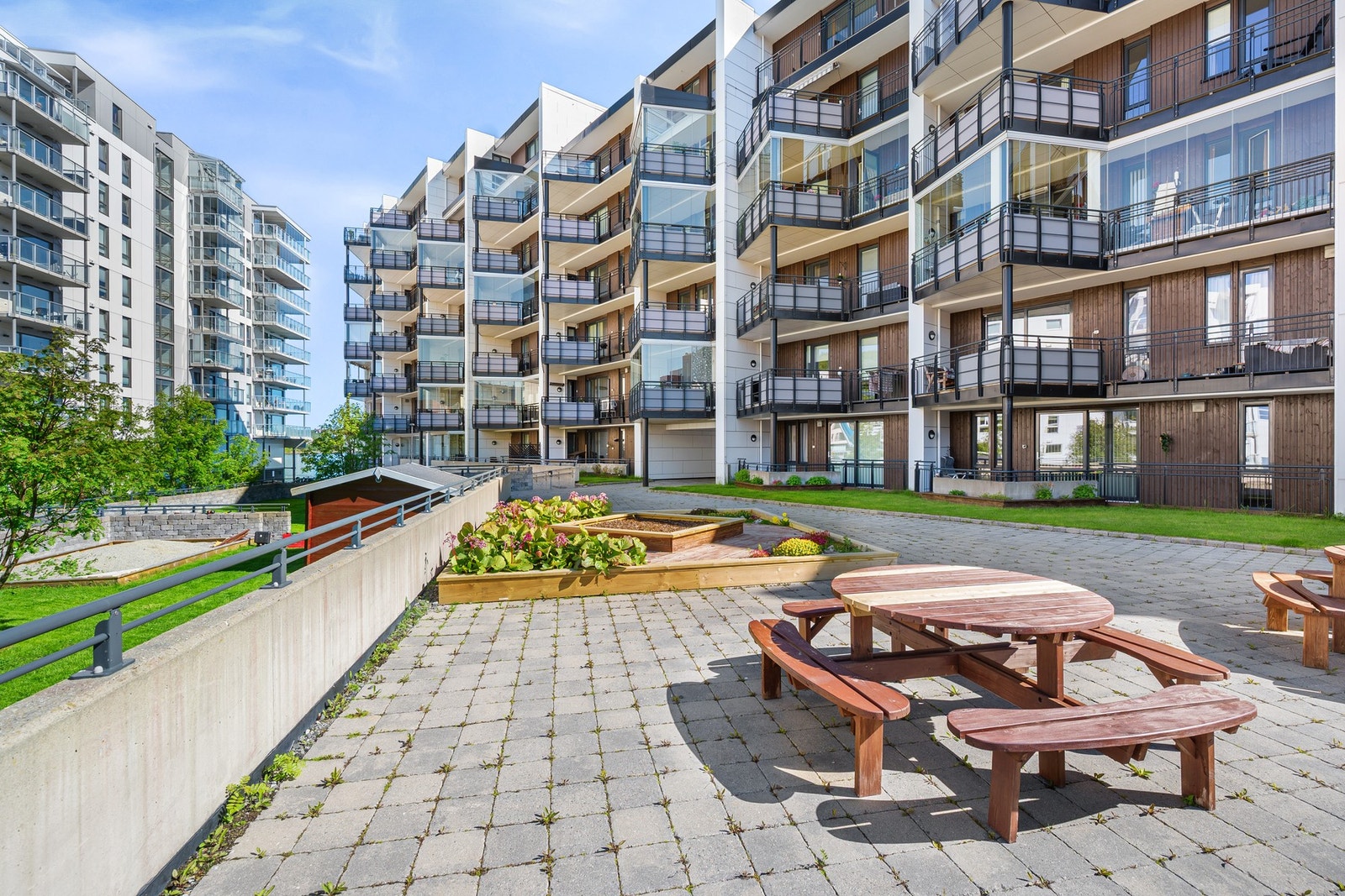Meget pent opparbeidede utearealer med hage, beplantning, sittebenker og lekeplass Galleribilde