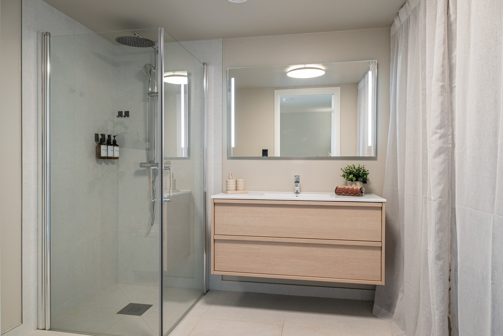Badet er delikat innredet med store, lyse fliser på gulvet og en kombinasjon av malte flater og lyse fliser på vegg. I gulvet har man også varmekabler for ekstra komfort. Galleribilde