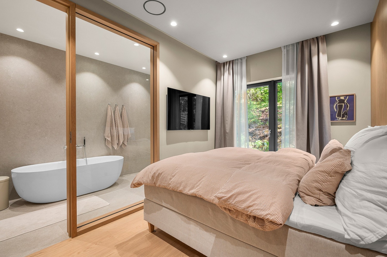 Hovedbadet er en eksklusiv forlengelse, elegant adskilt fra soverommet med en spesialtilpasset glassvegg som skaper en luftig og hotellinspirert atmosfære. Galleribilde