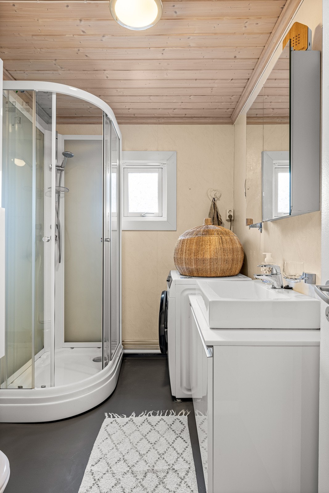 Badet er utstyrt med dusjkabinett, toalett, servant med innredning og opplegg for vaskemaskin. Galleribilde