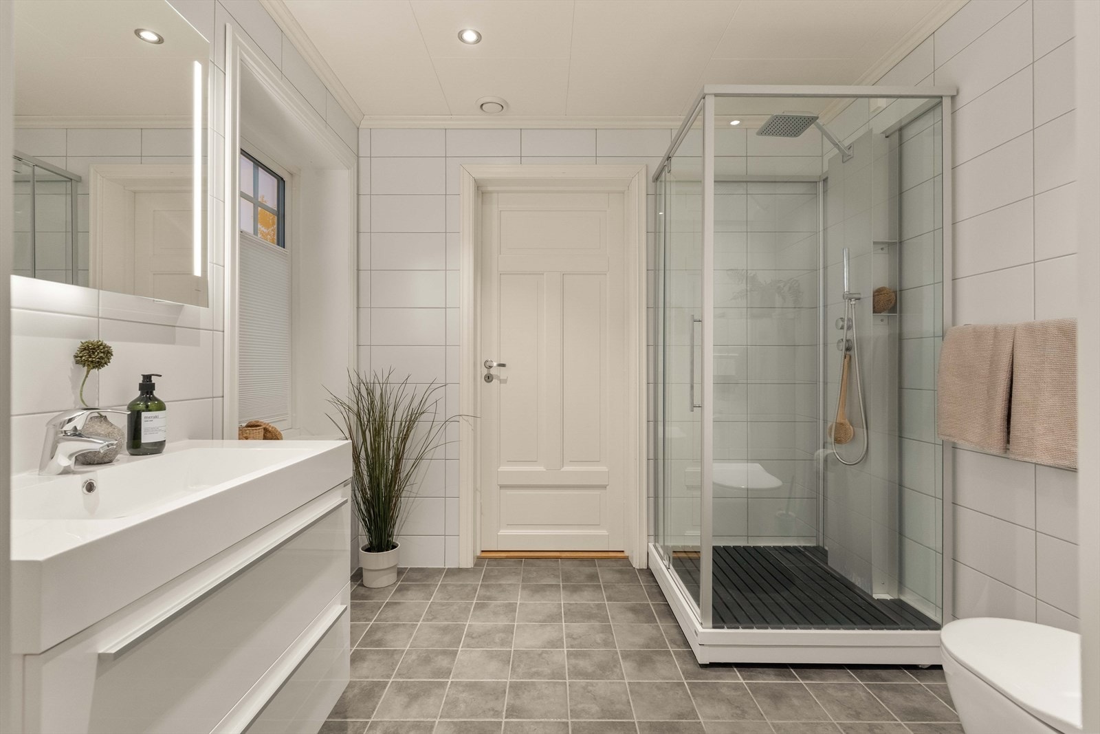 Badet i første etasje er pent og lyst, med veggmontert toalett og dusjkabinett i herdet glass som gir et rent uttrykk. Galleribilde