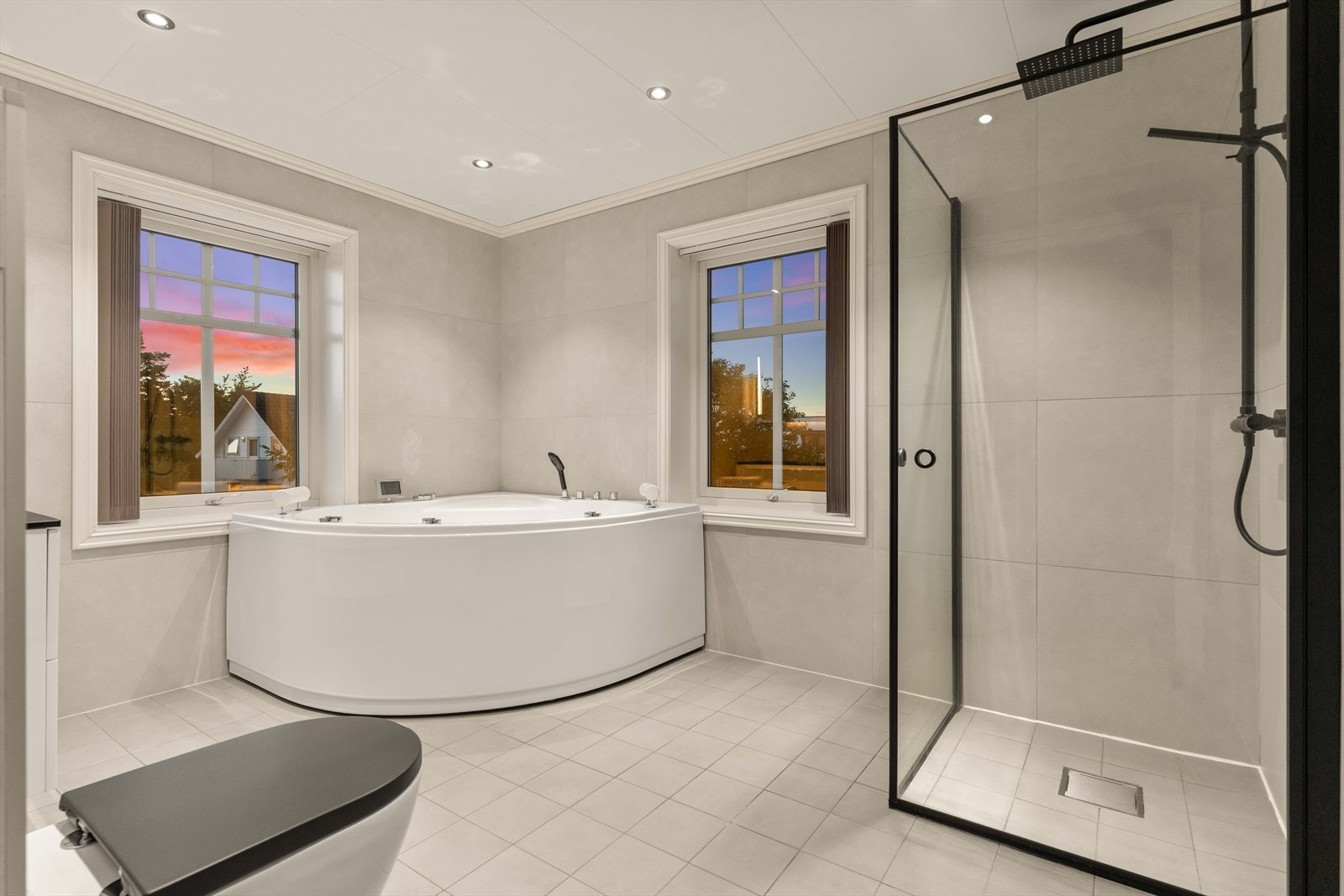 Badet i andre etasje fremstår moderne og innbydende, med veggmontert toalett, dusj med herdet glass og et romslig boblebadekar som gir en behagelig spafølelse. Galleribilde