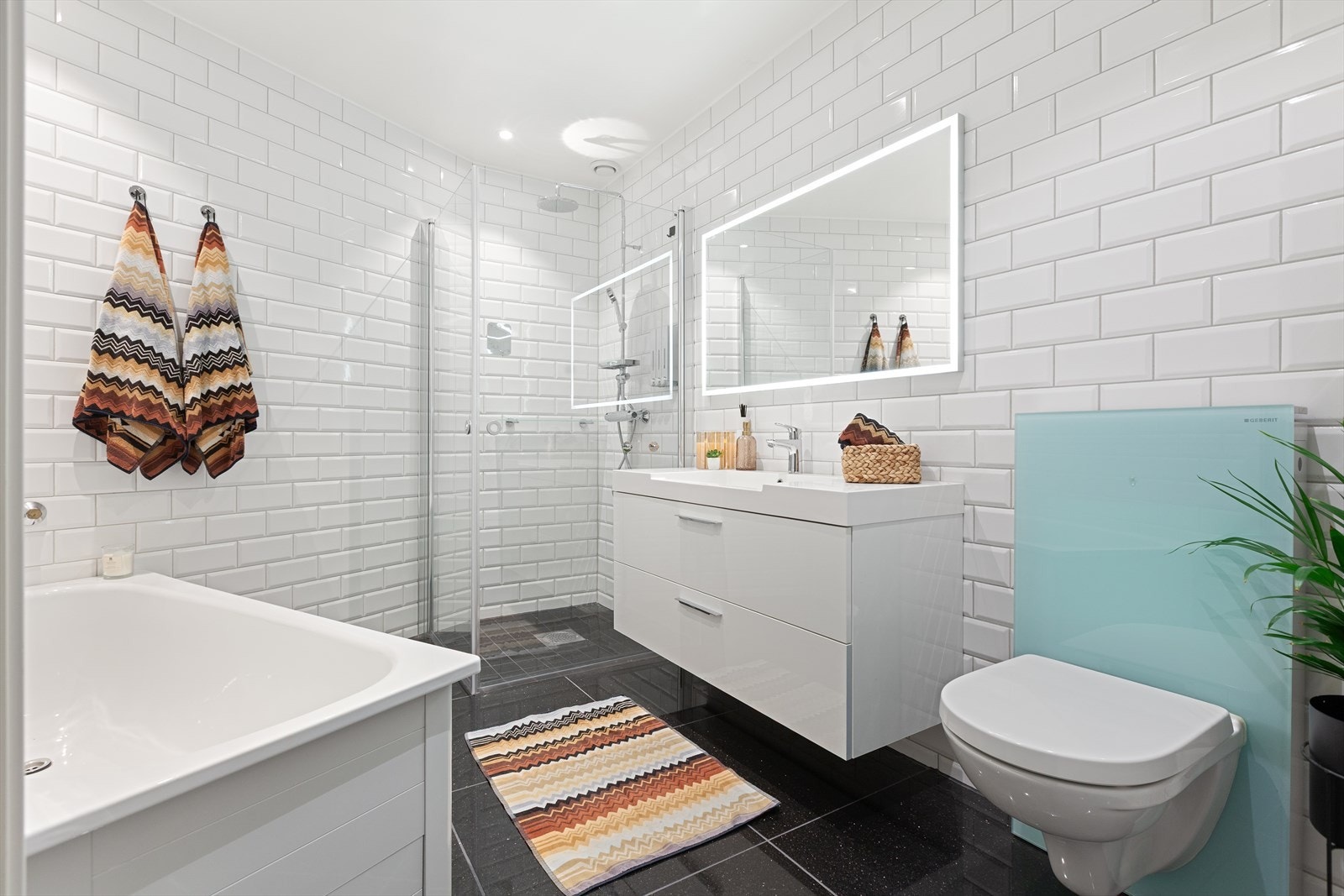 Pent flislagt bad med 60*60 cm Black Galaxy på gulv. Badet er i delikat utførelse og er utstyrt med bred skuffeinnredning med overliggende servant. Vannbåren varme i gulv. Badekar med armatur kan kobles på. Galleribilde