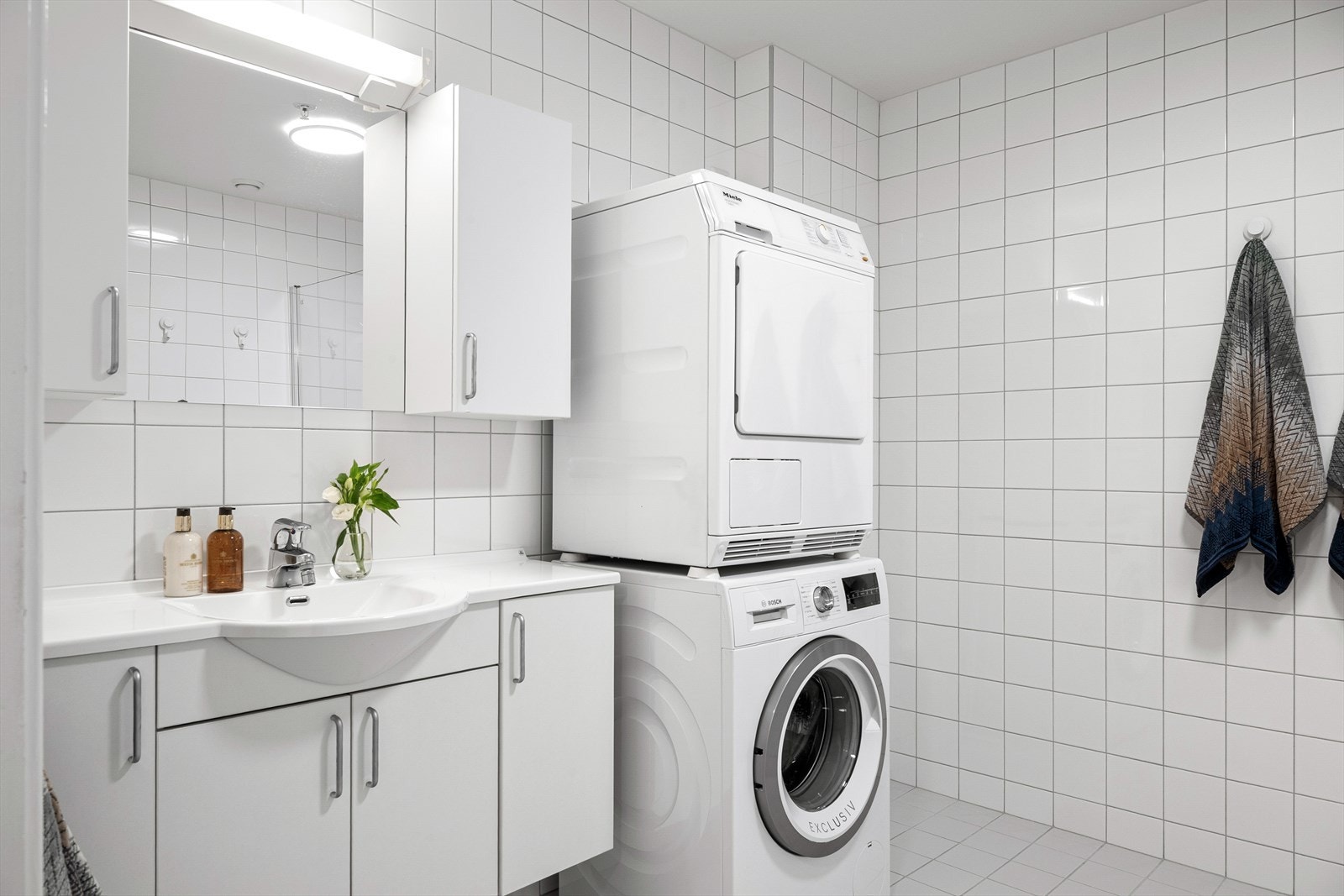 Badet er innredet med toalett, vask i seksjon, speil med belysning og dusjhjørne. Det er opplegg for vaskemaskin og tørketrommel på badet. Galleribilde