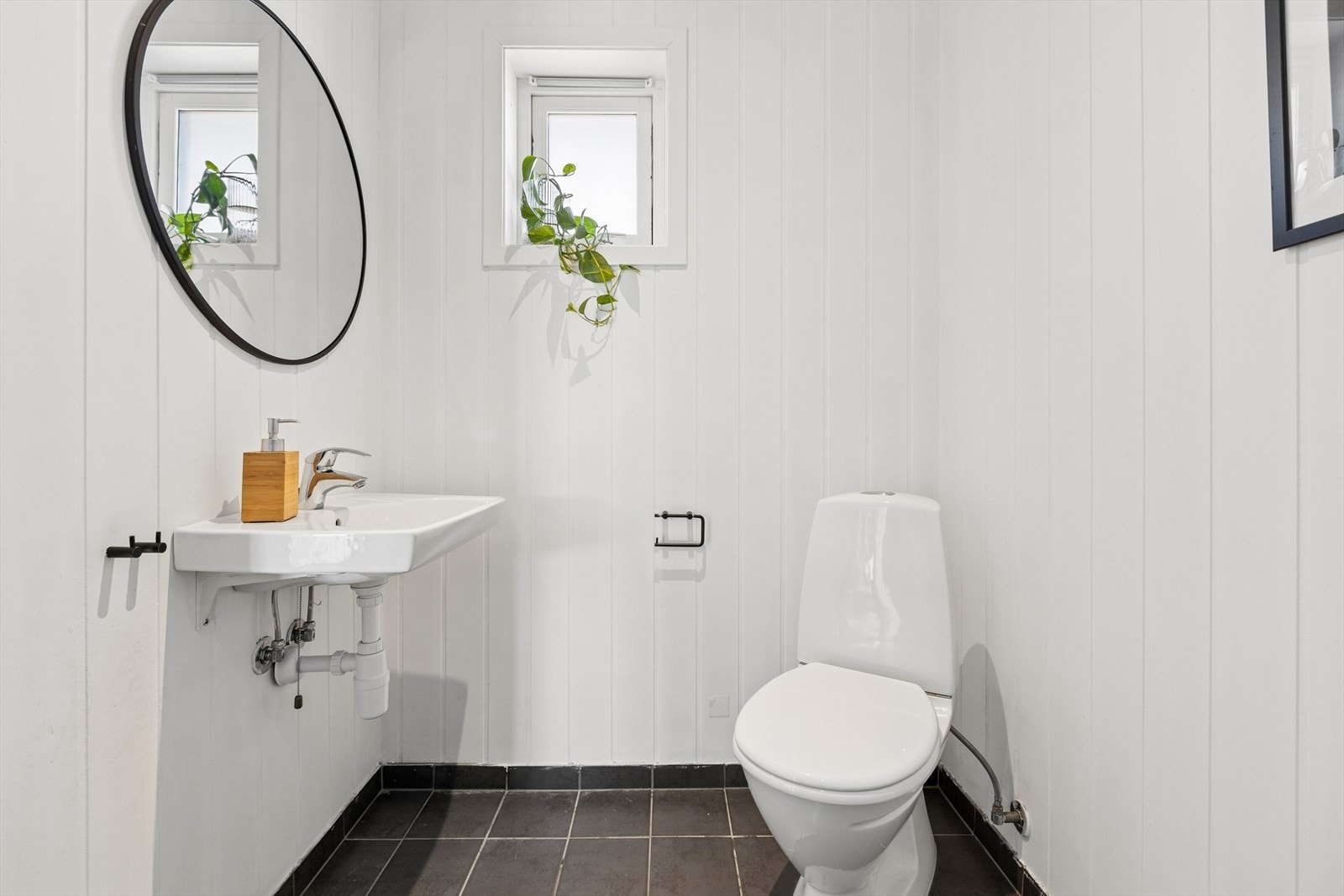 Praktisk wc/vaskerom har mørke fliser på gulv og veggene har mdf panel. Videre er rommet utstyrt med gulvmontert toalett, servant, bereder og opplegg for vaskemaskin. Rommet har ingen varmekilde. Balansert ventilasjon. TG3 i rapporten. Galleribilde