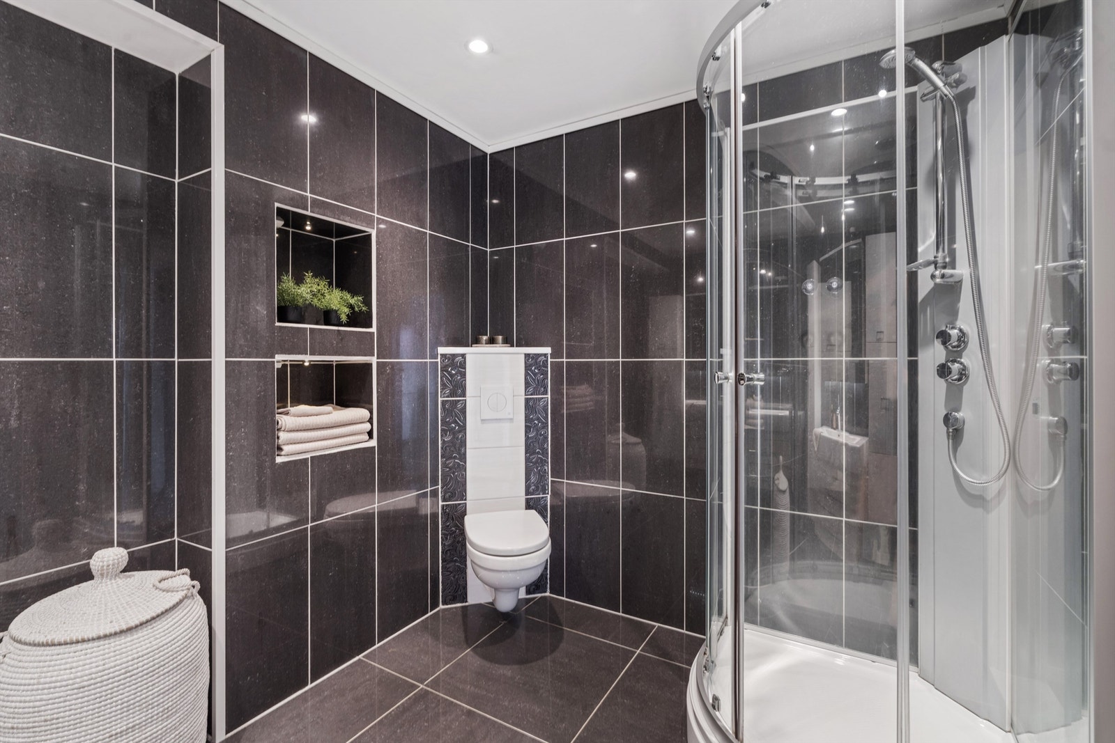 Badet er utstyrt med dusjkabinett og vegghengt toalett. Galleribilde