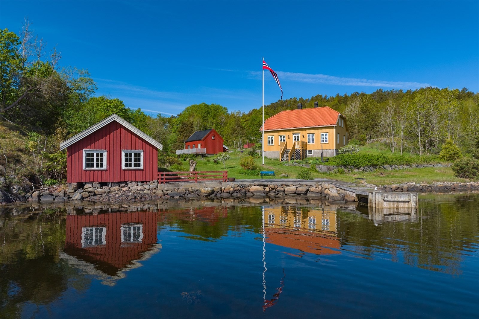 Våningshuset, gjestehuset og sjøbuen sett fra vannet. Galleribilde