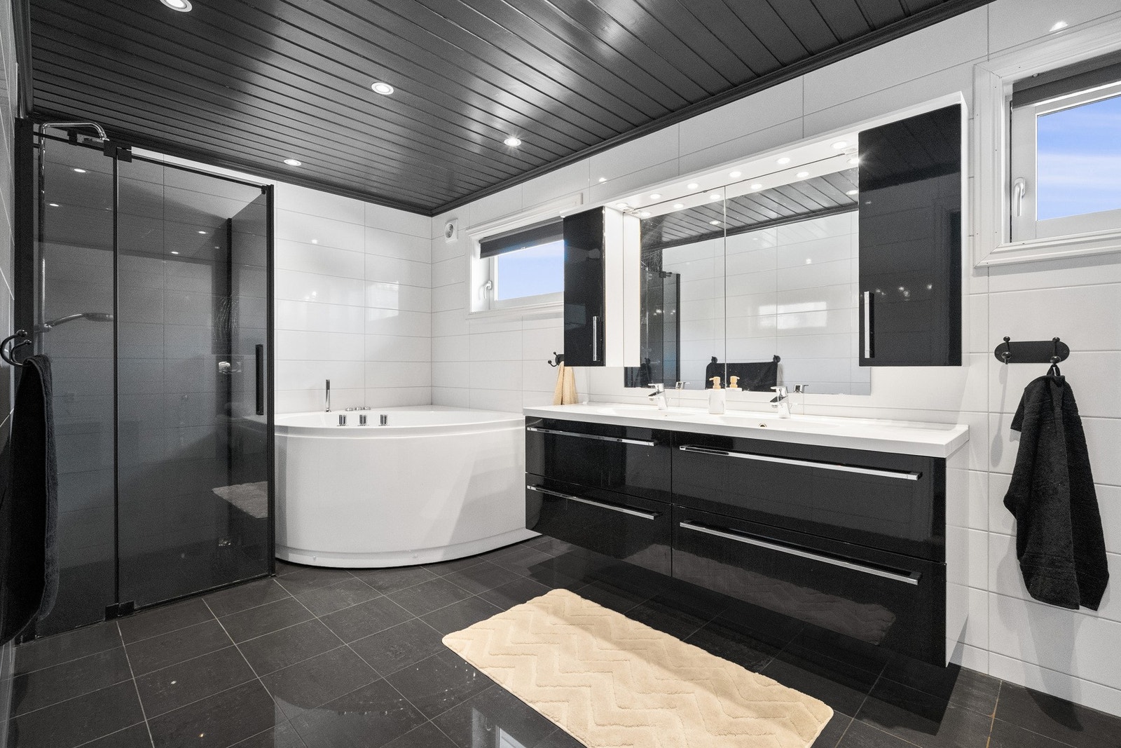 Badet er innredet med dobbel servantinnredning, dusjhjørne med regnfallsdusj, toalett og et romslig boblebadekar. Galleribilde