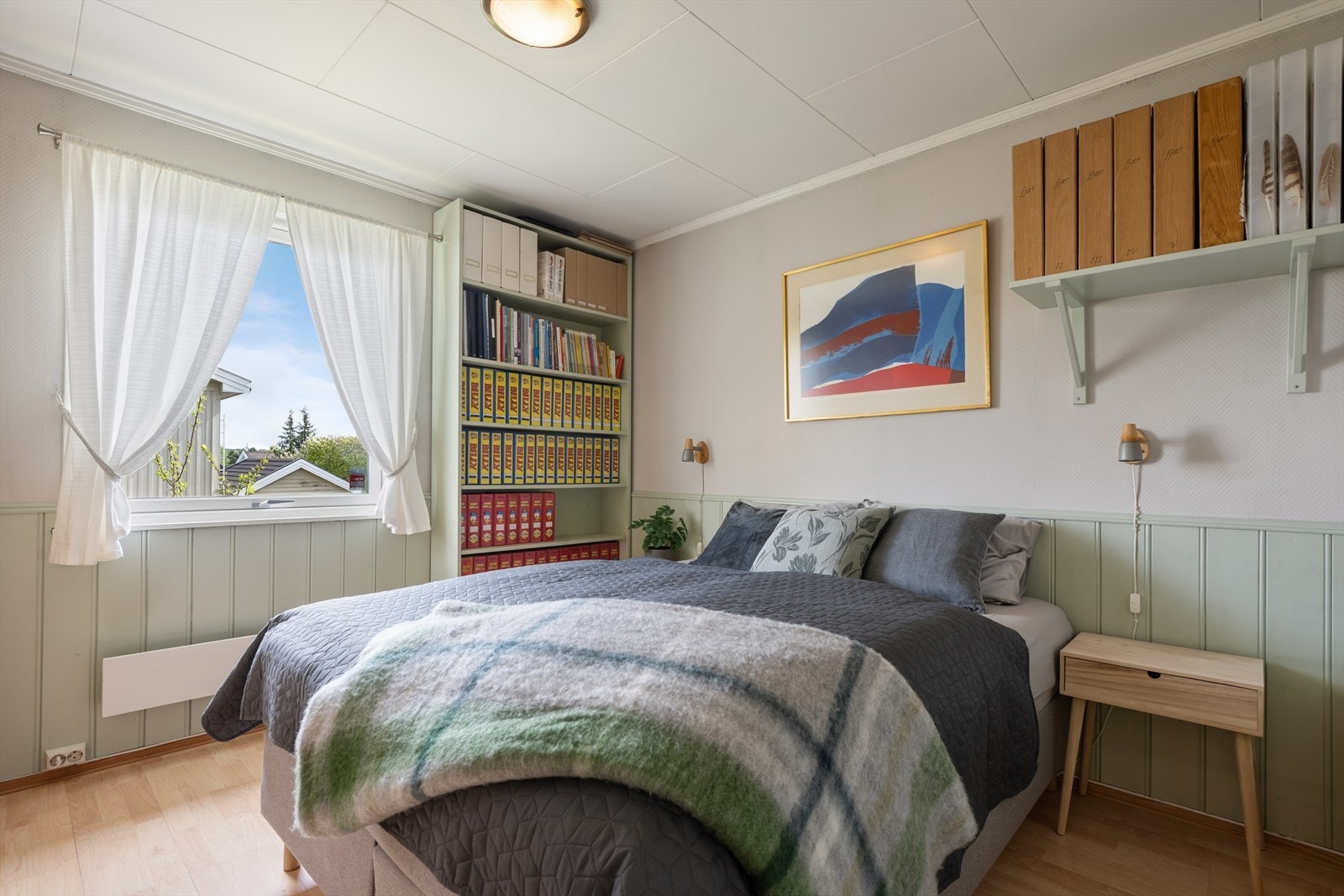 Et av soverommene i første etasje, med laminat på gulvet og malte flater. Galleribilde