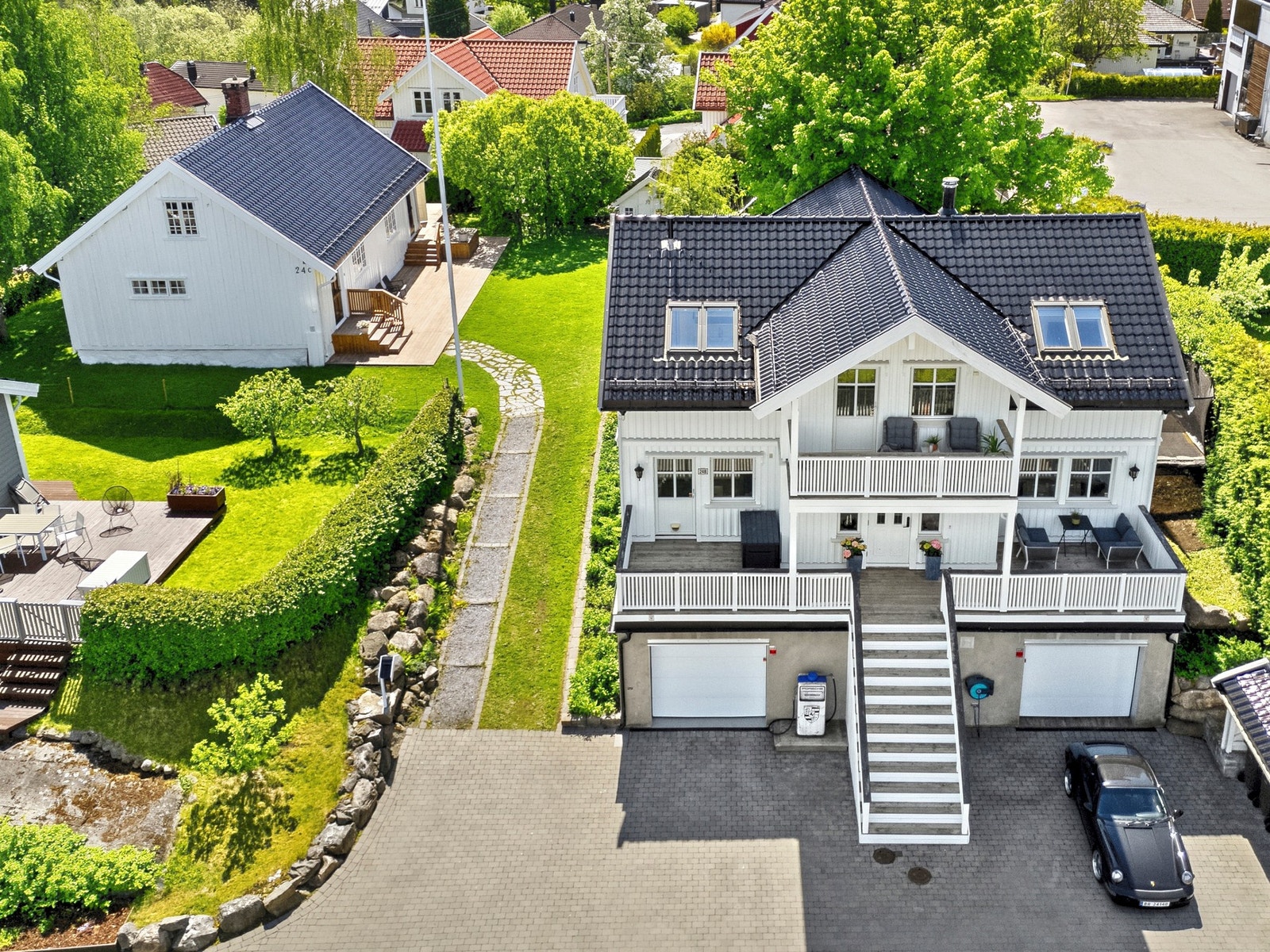 Gårdsplassen er steinsatt og det er innkjøring til to garasjer i underetasjen, med plass til totalt fire biler. Galleribilde