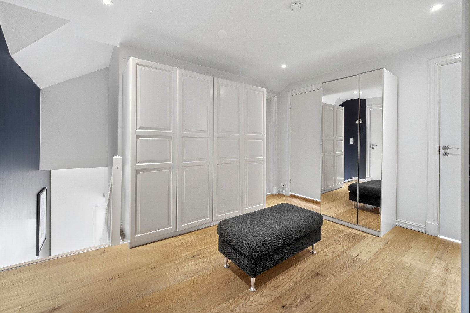 Gangen utenfor soverommene er innredet med garderobeskap på tre sider og har downlights i taket. To skaprekker har hvite fronter og ett har praktiske speilfronter. Galleribilde
