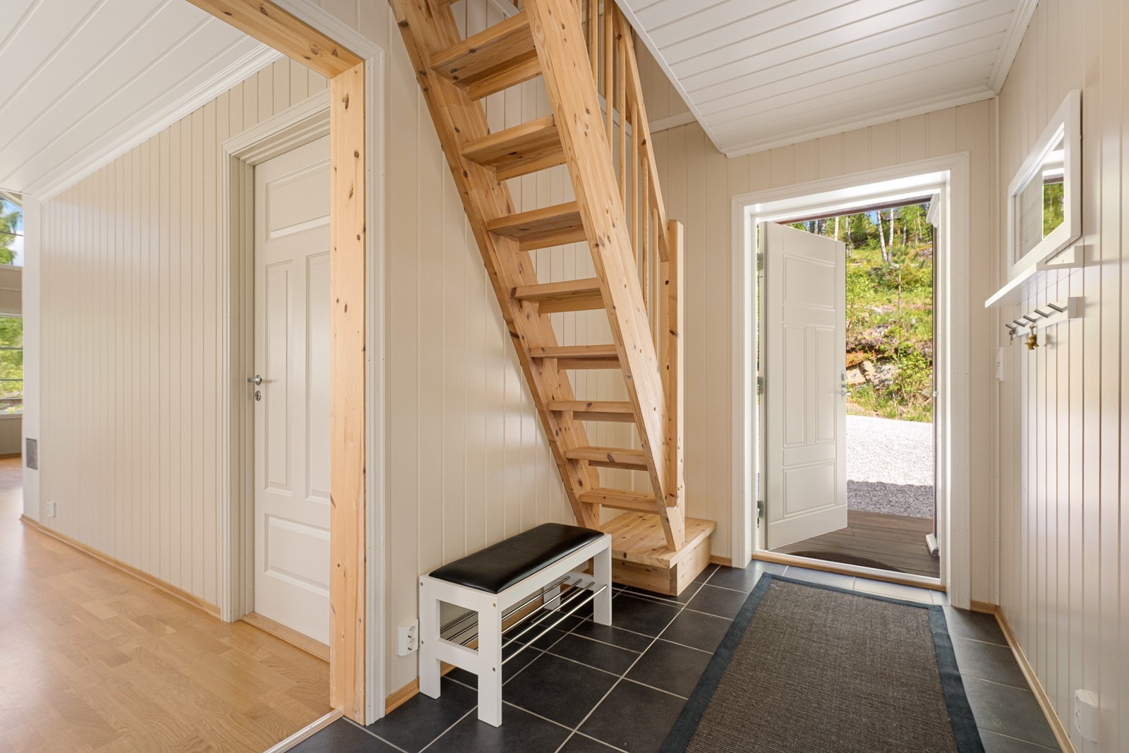 Vel inne har entreen sorte gulvfliser og beige panelplater. Her er det plass til å sette fra seg skoene og henge fra seg yttertøyet. Galleribilde