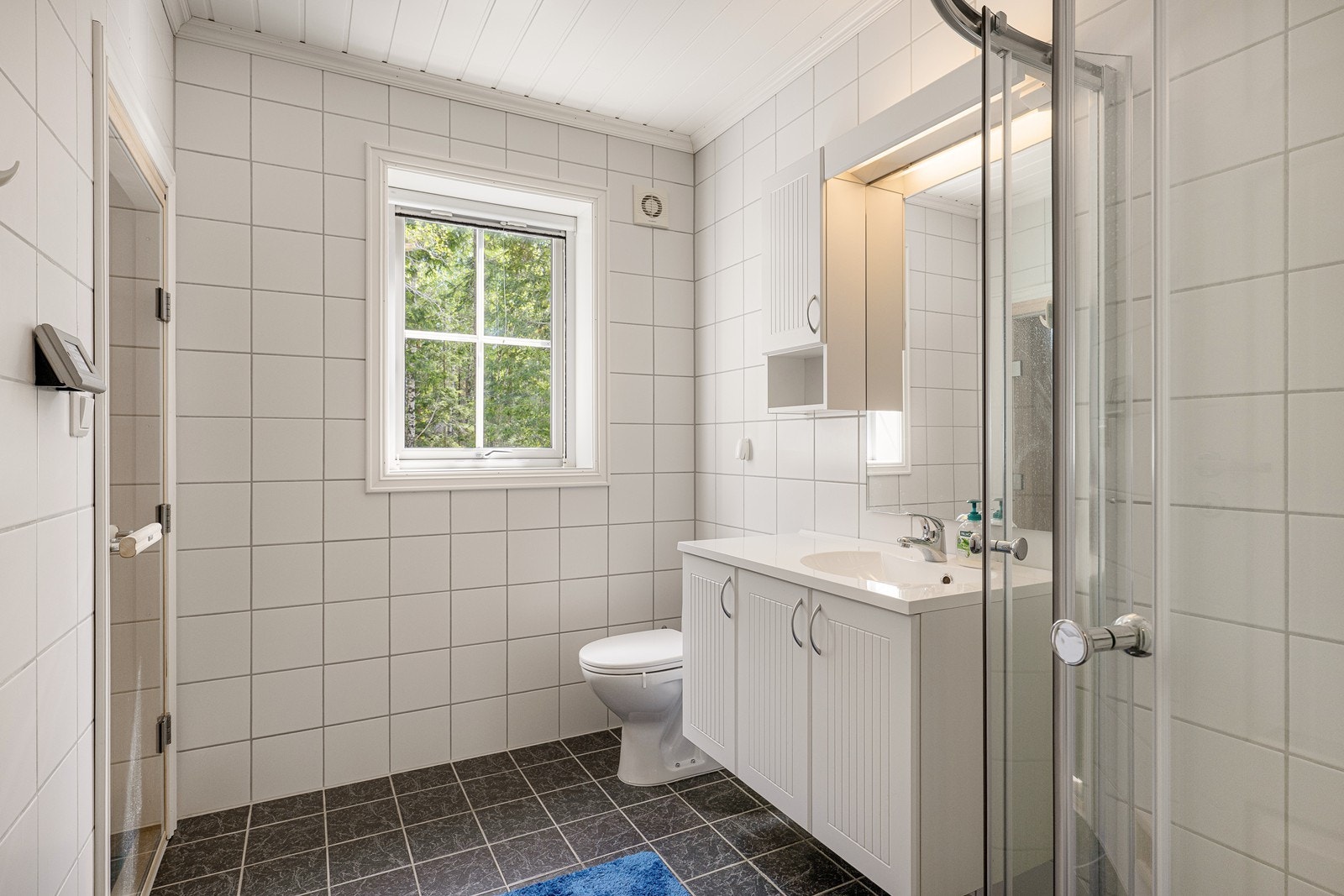 Dagene får en god start på badet, innredet med hvite veggfliser og mørke gulvfliser. Galleribilde