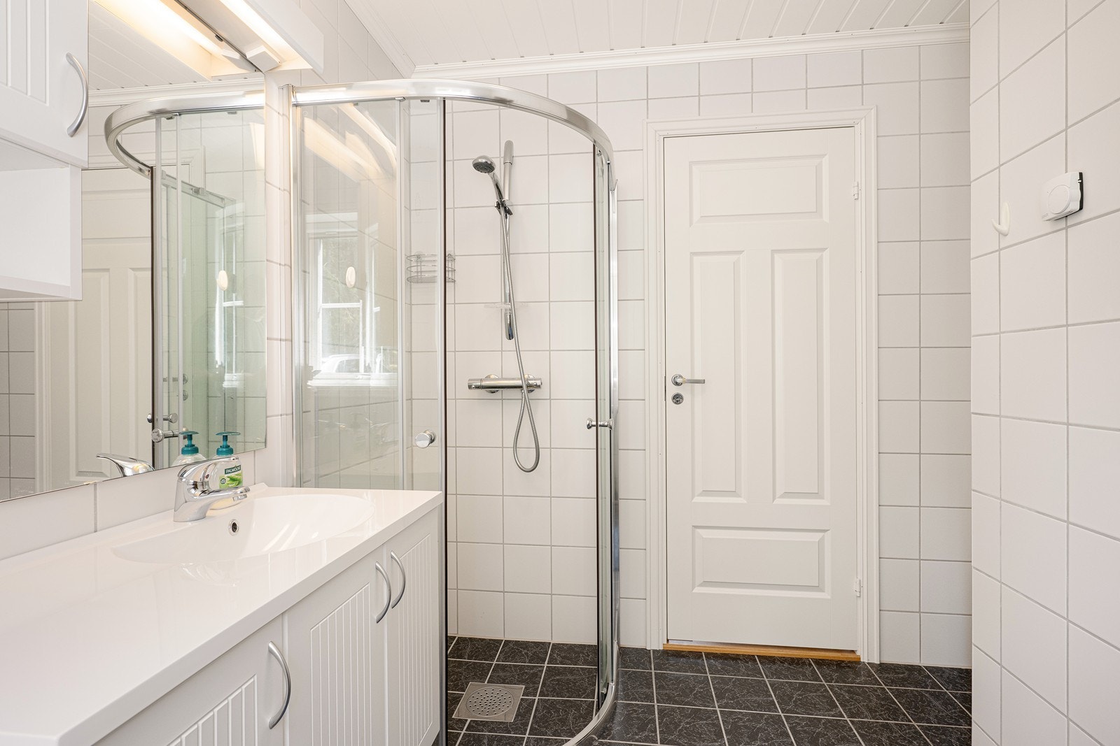 Varme er lagt i gulvet, og i tillegg til toalettet har badet opplegg for vaskemaskin og et dusjhjørne med skyvedører av glass. Galleribilde