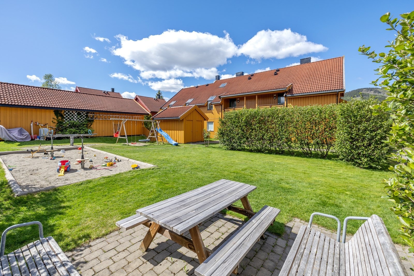 Fine fellesområder med lekeplass og sittegrupper på realsameiets tomt, som seksjonen har ideell andel på 1/20. Galleribilde