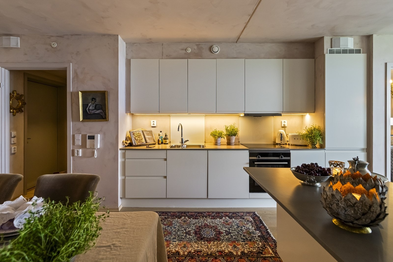 Kjøkkenet fra HTH har en tidløs, stilren innredning med lyse fronter, mørke benkeplater og integrerte hvitevarer, inkludert doble kjøl-/fryseskap, koketopp, komfyr og oppvaskmaskin. Galleribilde