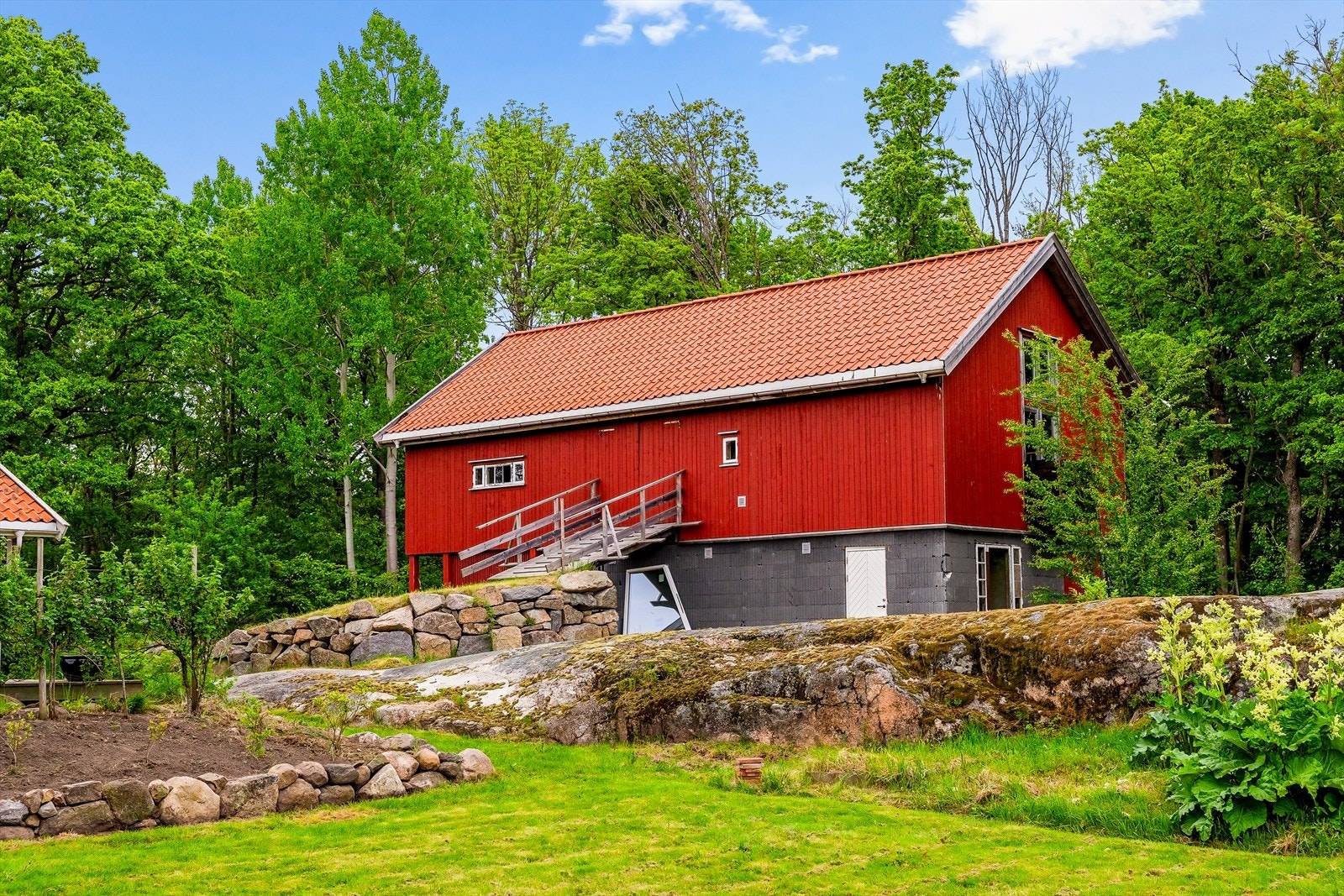 Uthuset sett fra hagesiden, med svaberg som en del av terrenget. Galleribilde