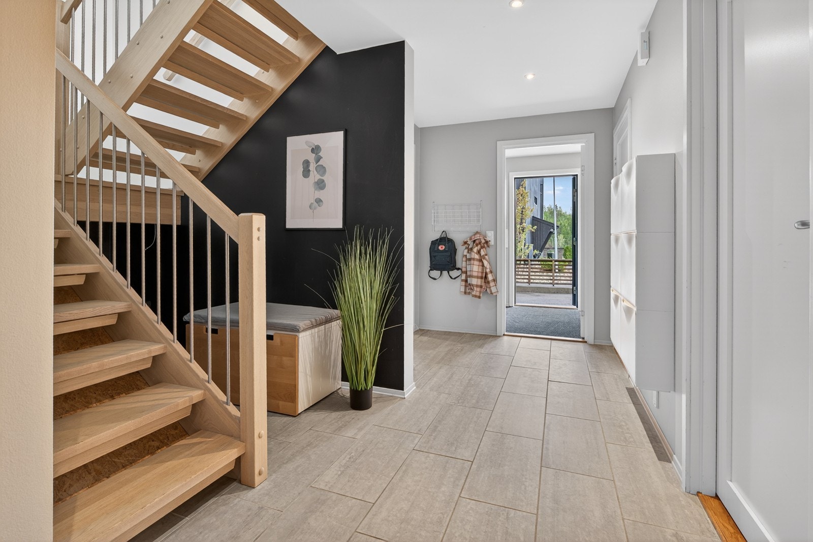 Romslig hall med eiketrapp, fliser, varmekabler og skoskap Galleribilde
