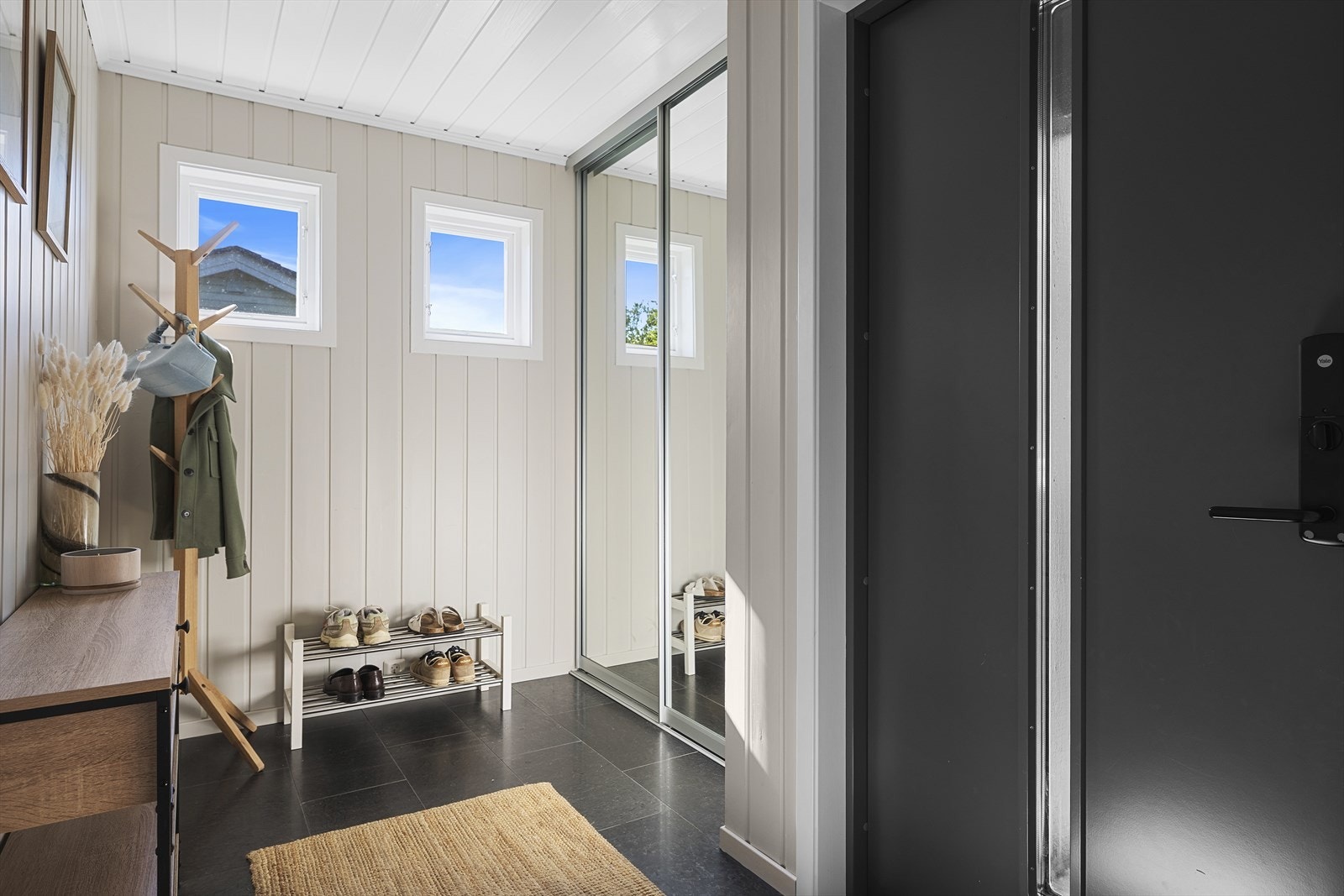 Fra hyggelig inngangsparti, trer du inn i en lys entré med god plass til sko og yttertøy. Praktisk skyvedørsgarderobe med speilfronter Galleribilde
