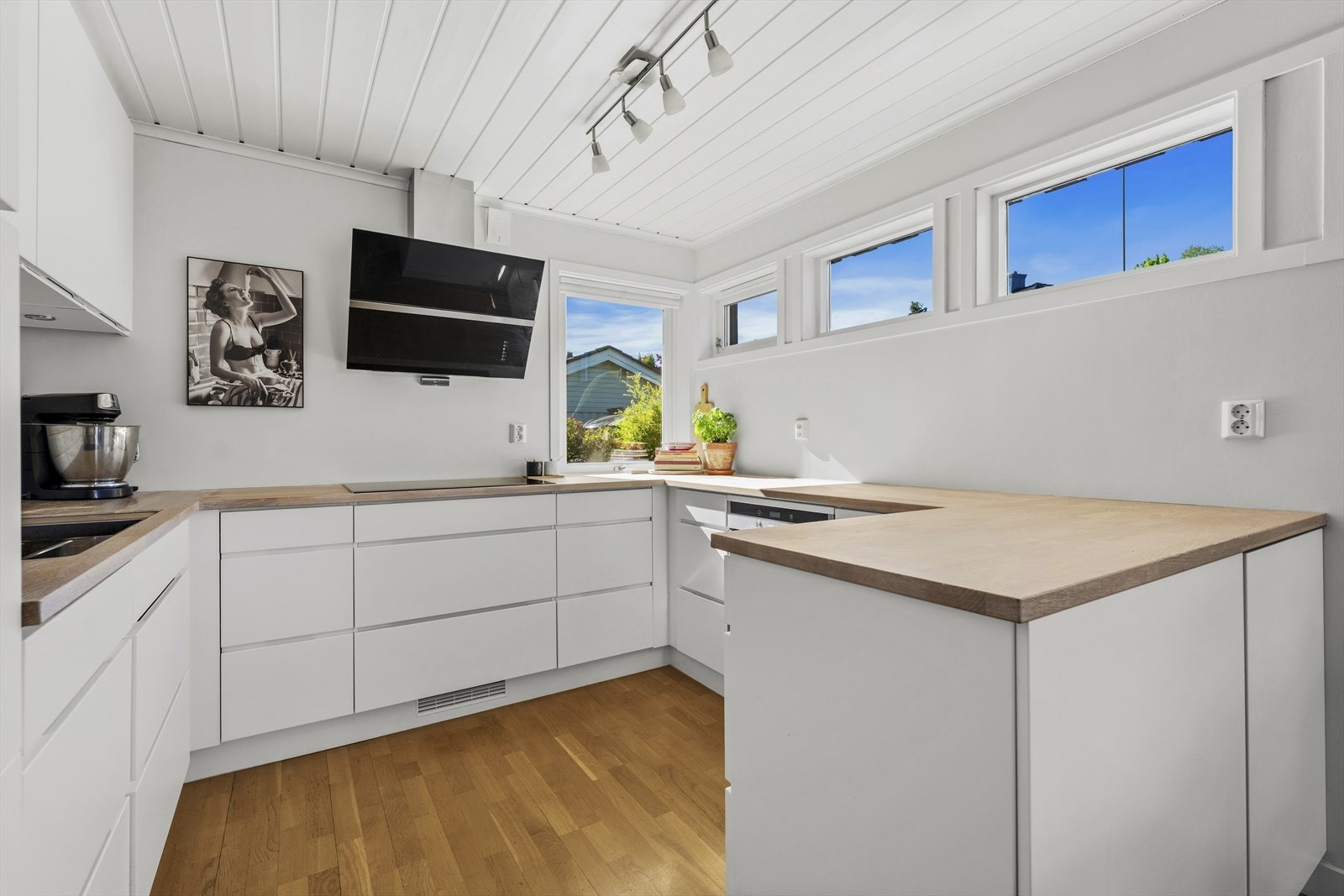 Delikat kjøkken med hvite, slette fronter med grepskant og heltre benkeplate Galleribilde